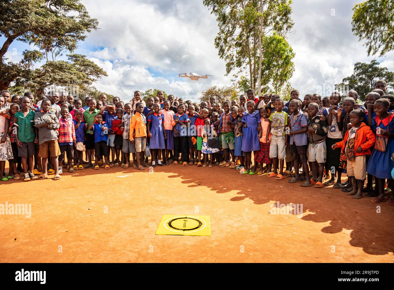 Schulkinder einer malawiischen Schulwache, während ein UAV (Drohne) von ihrem Schulgelände abhebt. Stockfoto