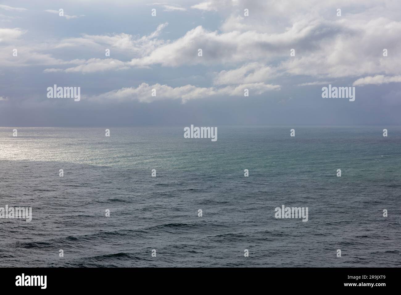 Sturmwolken über dem Pazifischen Ozean in der Dämmerung, grüne und graue Wasseroberfläche, Regendusche und Regenwolke. Stockfoto