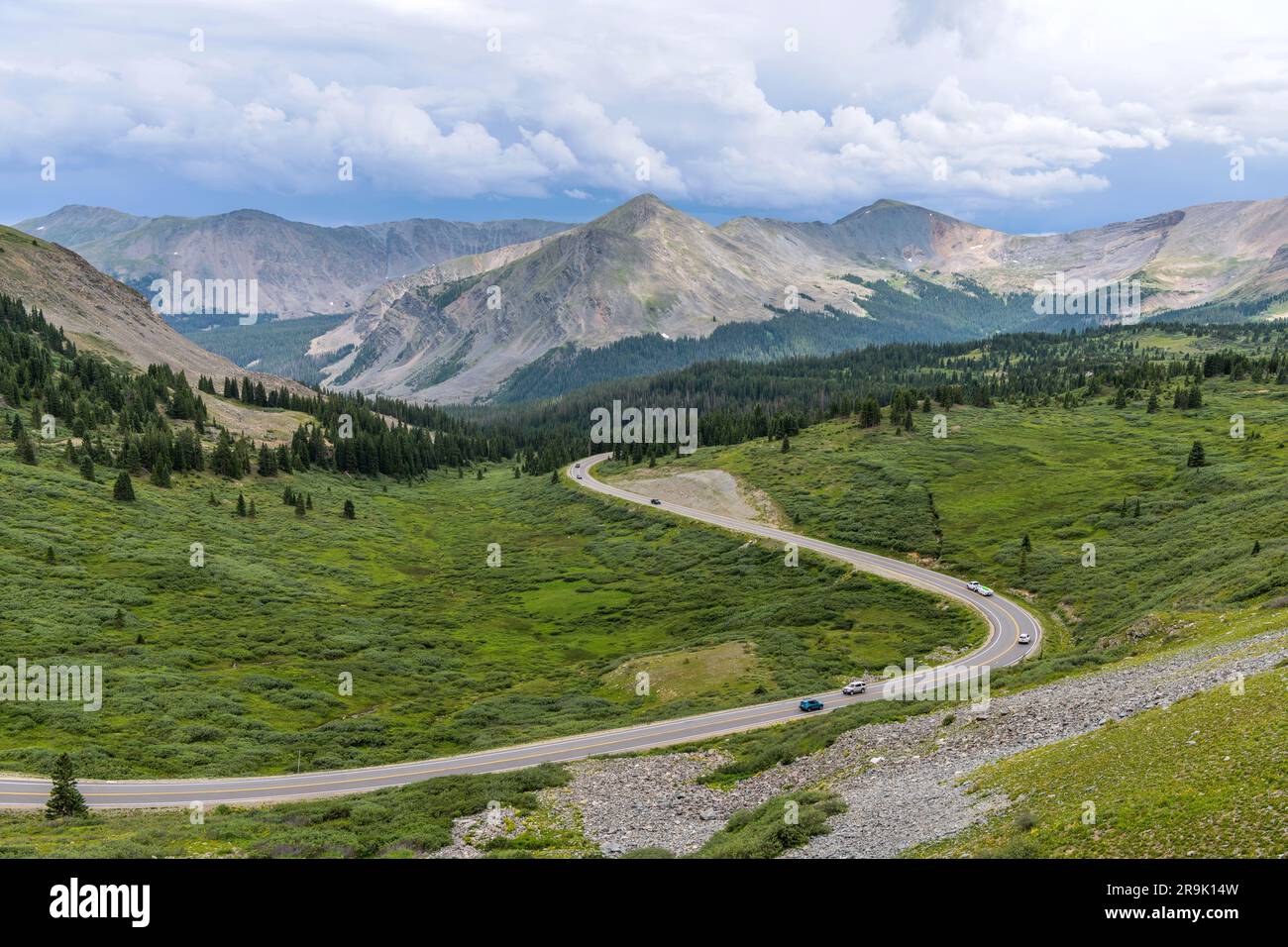 Cottonwood Pass - ein Sommerpanorama einer Bergstraße, die sich in einem grünen Tal östlich des Gipfels des Cottonwood Pass schlängelt. Crested Butte, CO, USA. Stockfoto