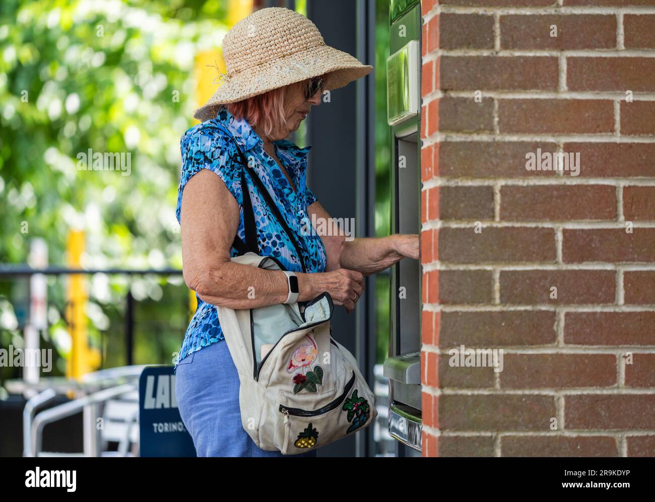Seniorin, die Geld in bar, an einem Geldautomaten, einem Geldautomaten oder einem Geldautomaten in Großbritannien bekommt. Stockfoto
