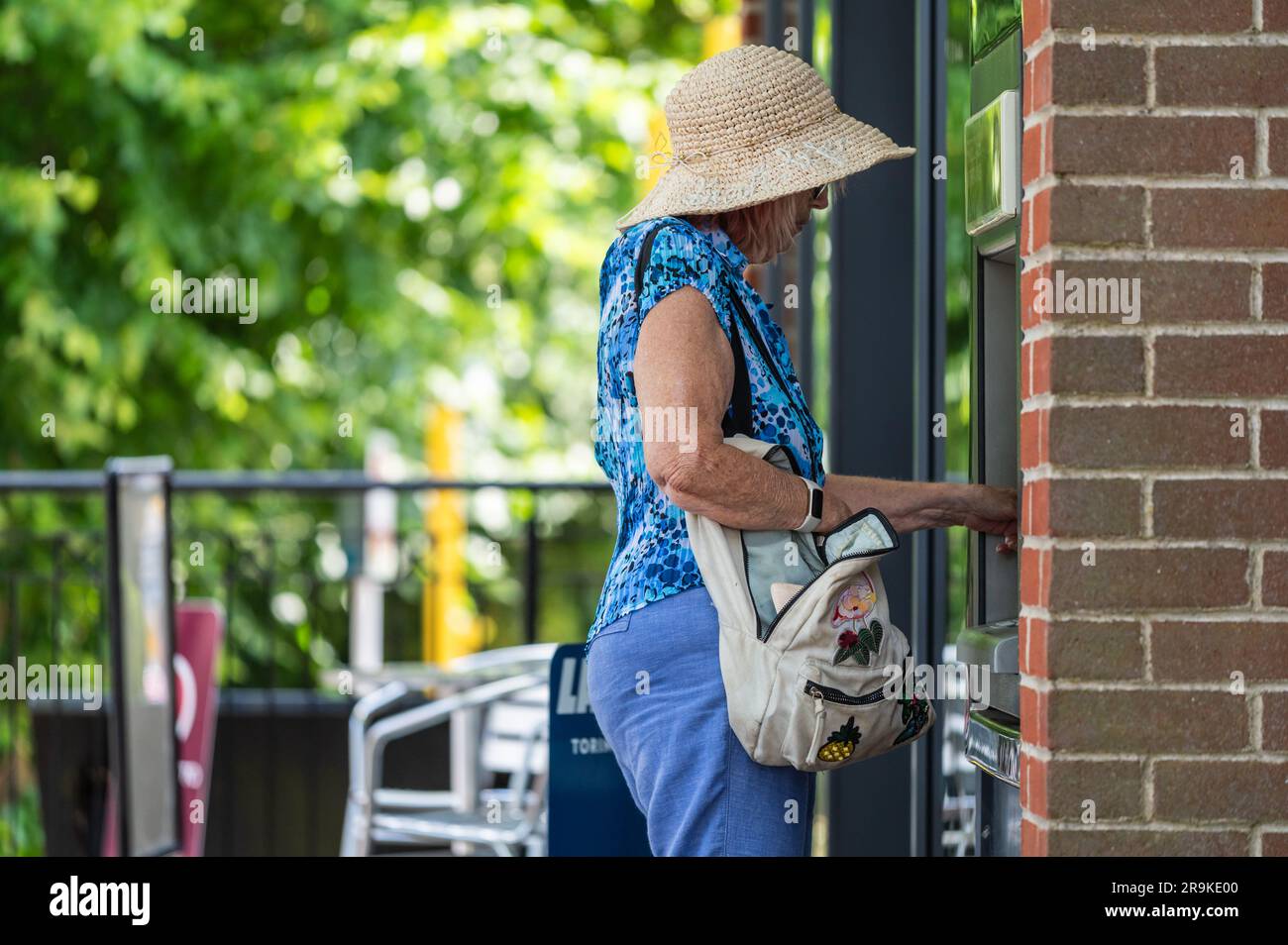 Seniorin, die Geld in bar, an einem Geldautomaten, einem Geldautomaten oder einem Geldautomaten in Großbritannien bekommt. Stockfoto