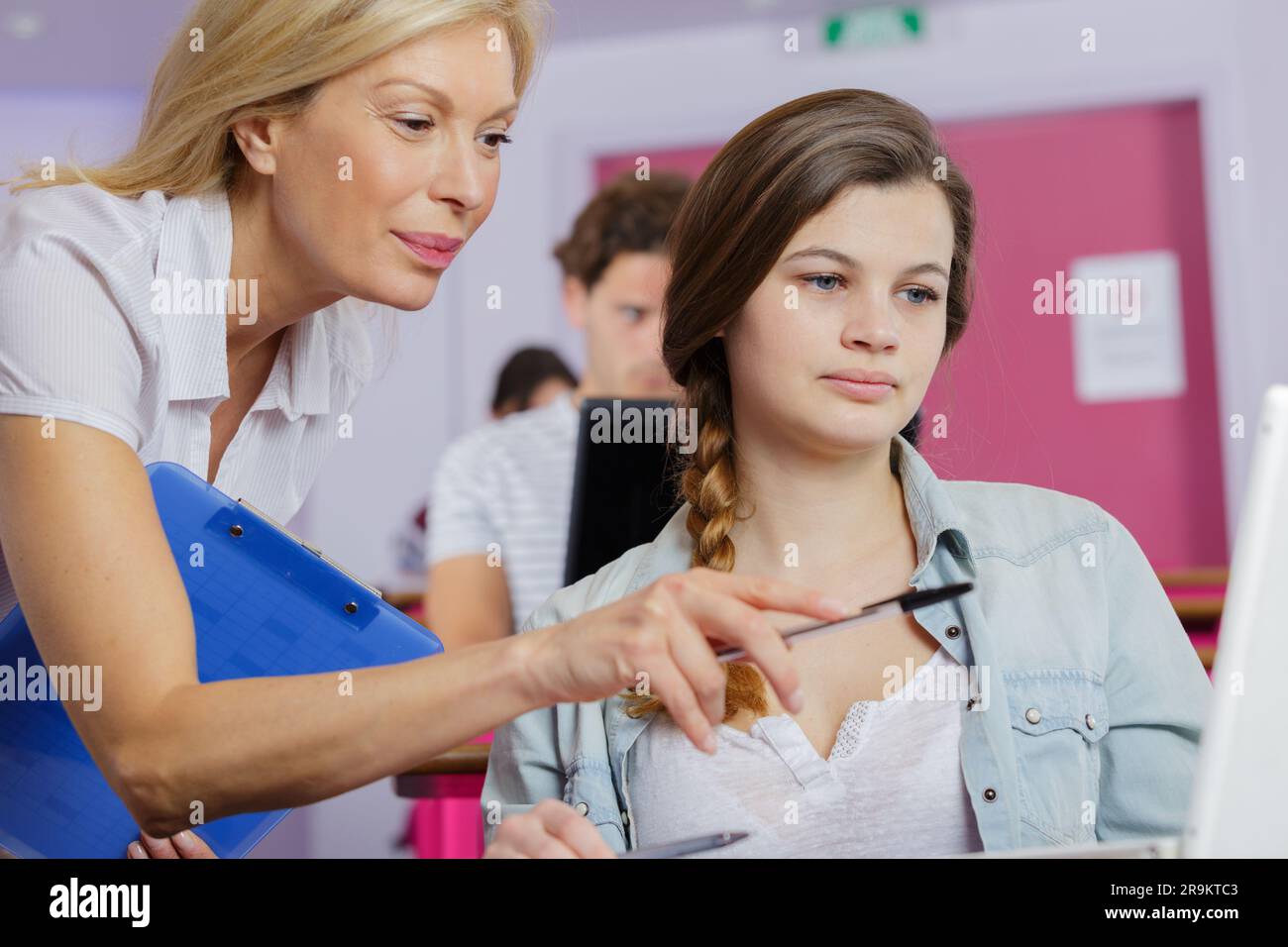 Reife Lehrerin, die der Schülerin beim Umgang mit dem Computer hilft Stockfoto