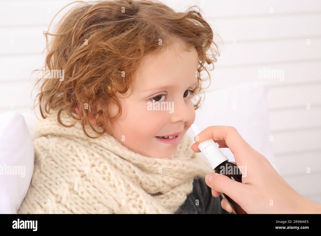 Mutter benutzt Nasenspray, um ihren kleinen Sohn drinnen zu behandeln, Nahaufnahme Stockfoto