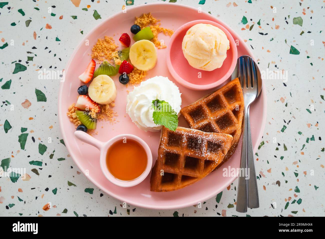 Waffel mit Eis, Schlagsahne, Banane, Erdbeere, Kiwi und Honig. Stockfoto