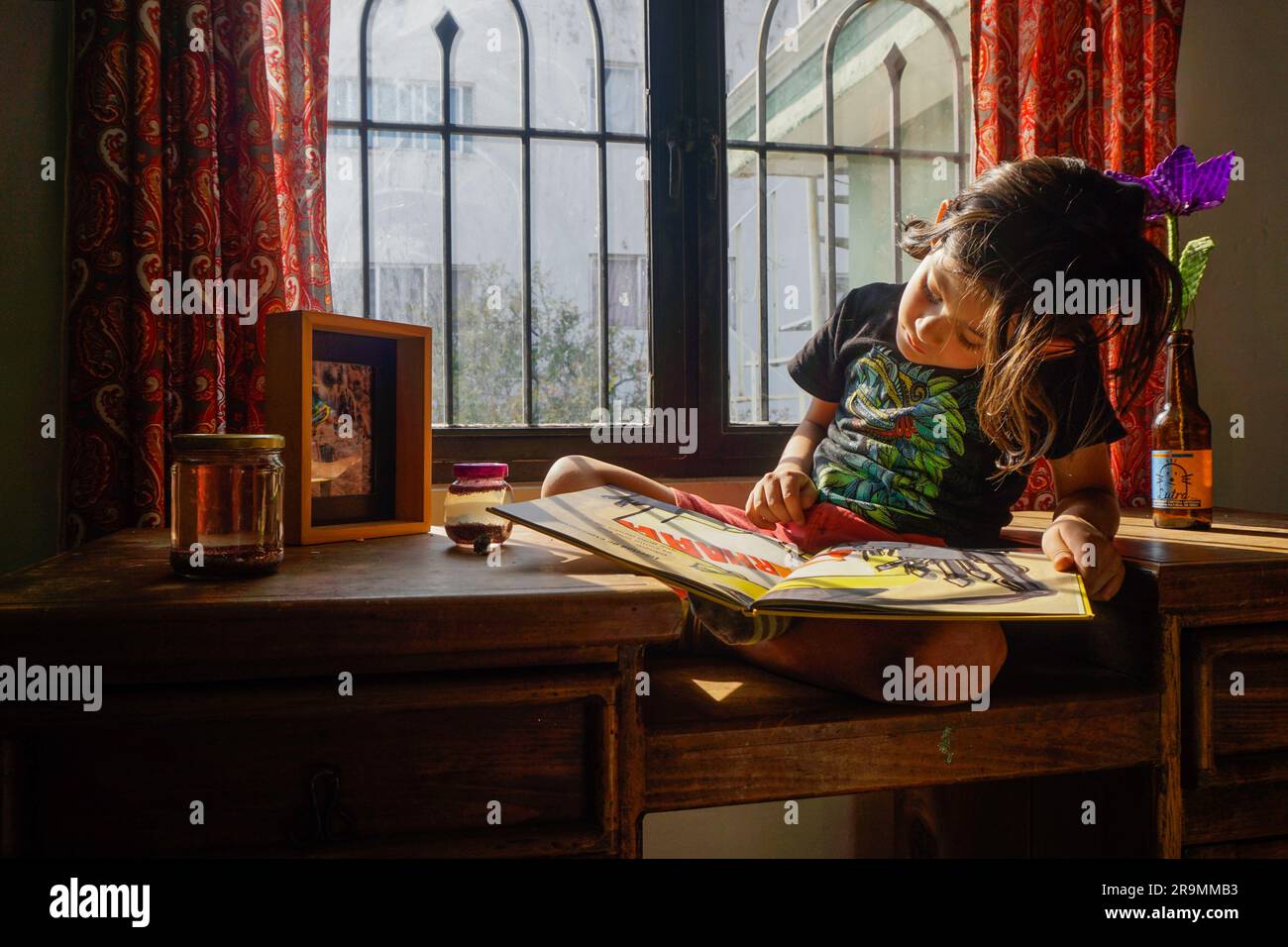 COSME Damián Peña Suárez del Real, der Sohn des Fotografen 7, liest am 30. März 2023 ein Buch neben einem Fenster in seinem Haus im Staat Mexiko. (Aline Suárez del Real/Global Press Journal) Stockfoto