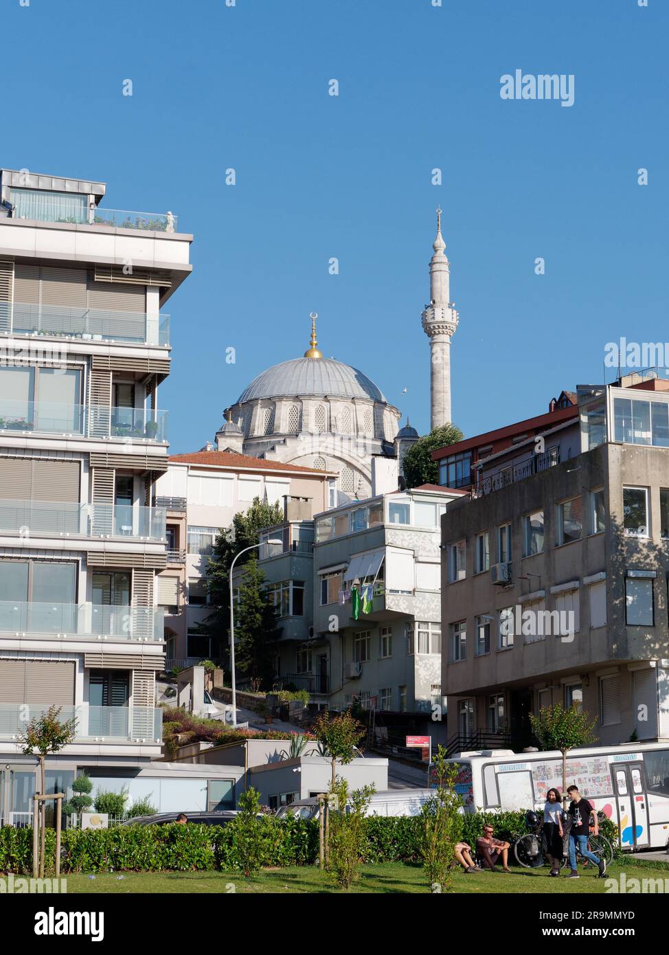 Moschee umgeben von Wohnwohnungen, während die Menschen auf einem Rasen in der Sommersonne sitzen, Uskudar, Istanbul, Türkei Stockfoto