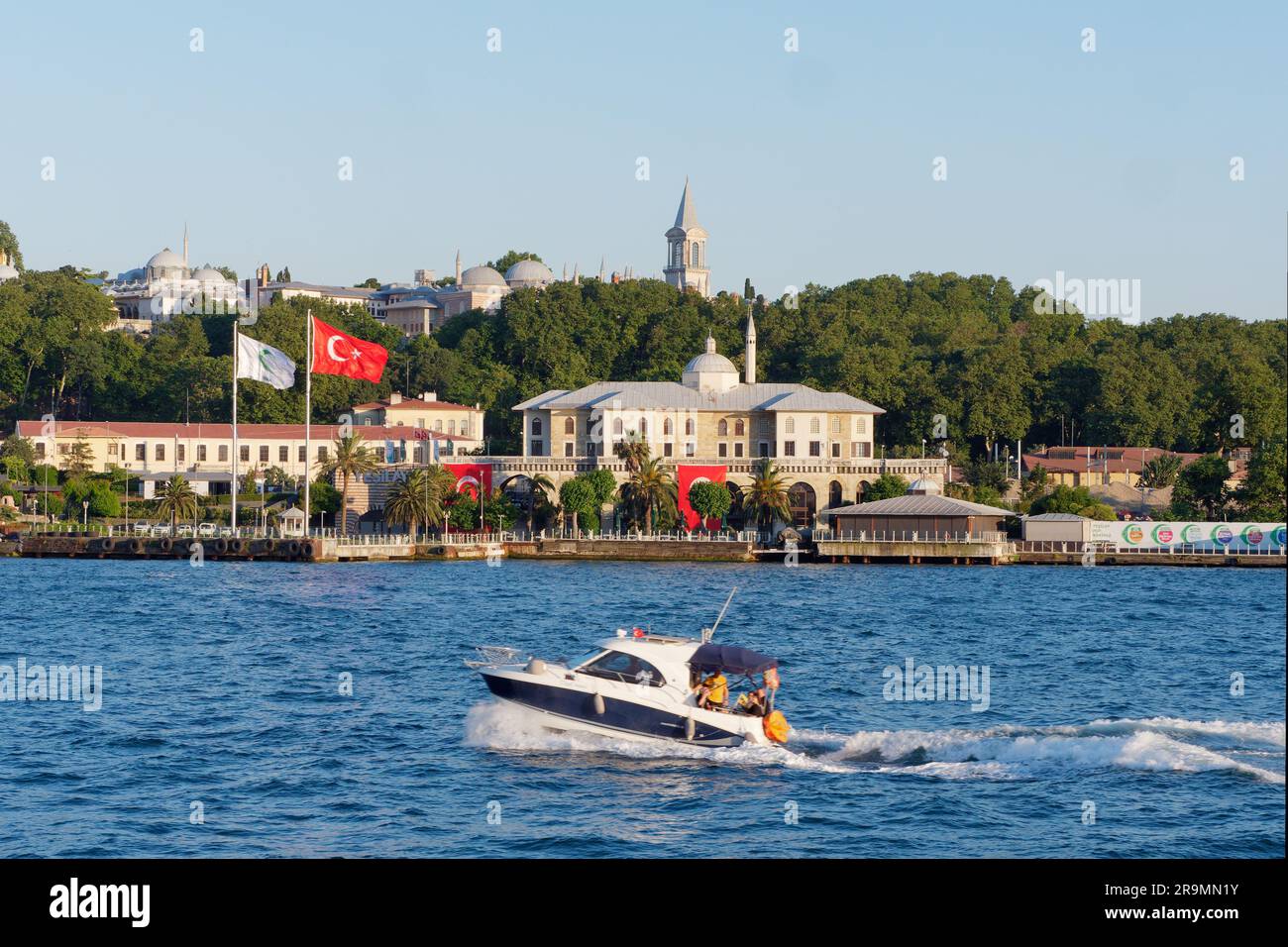 Schnellboot auf dem Bosporus, Istanbul, Türkei. Der Topkapi-Palast befindet sich auf dem Hügel hinter dem Viertel Fatih. Die türkische Flagge fliegt am Wasser Stockfoto