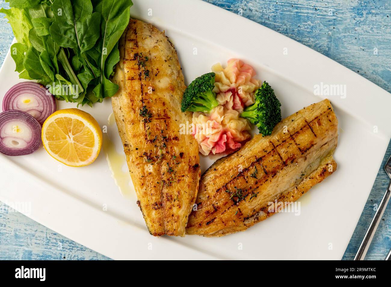 Gegrilltes Seebarschfilet mit Garnierungen in einem eleganten Restaurant Stockfoto