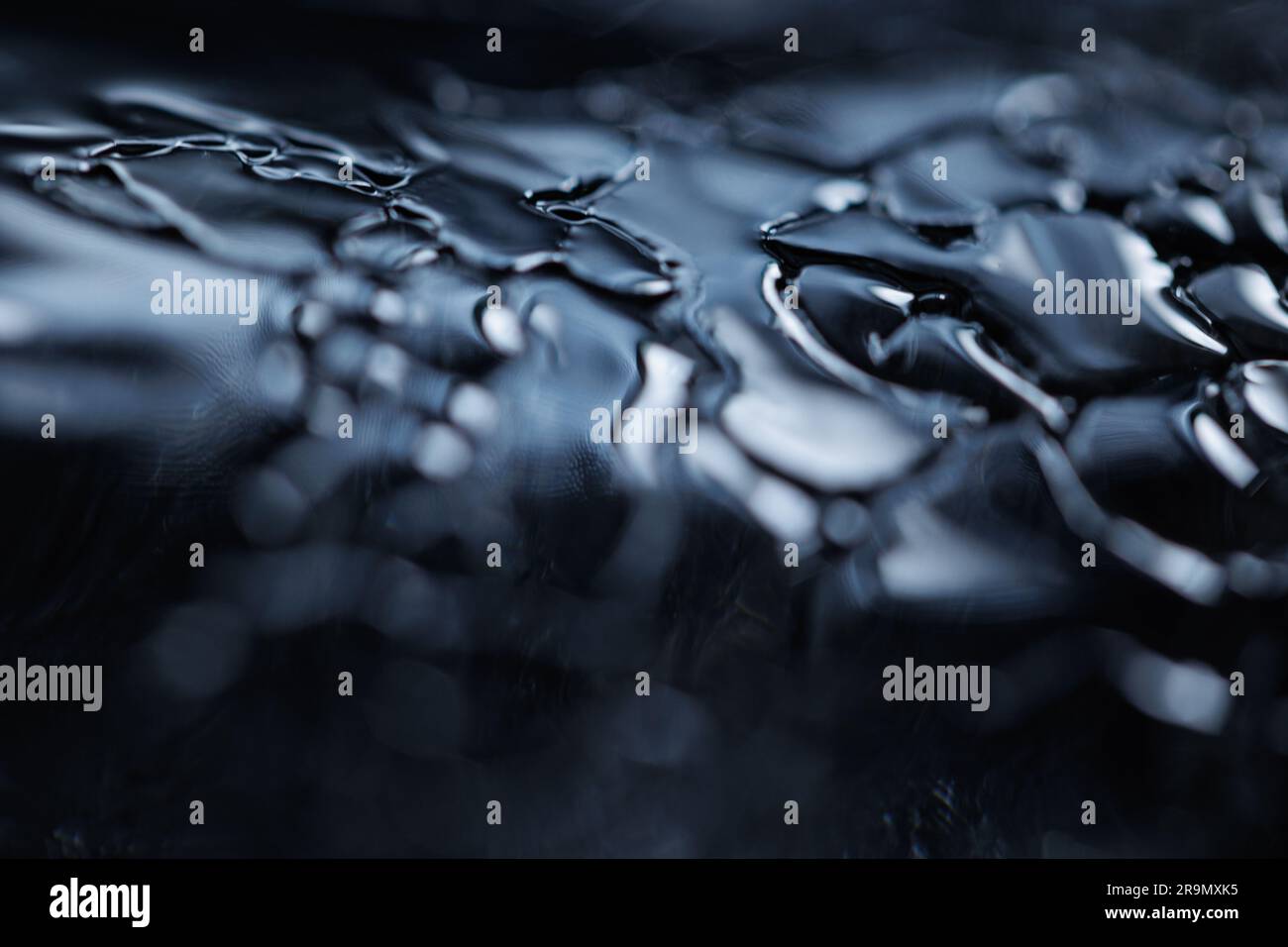 Eine Makroaufnahme von Wassertropfen auf einer schwarzen Oberfläche für Hintergrundbilder Stockfoto
