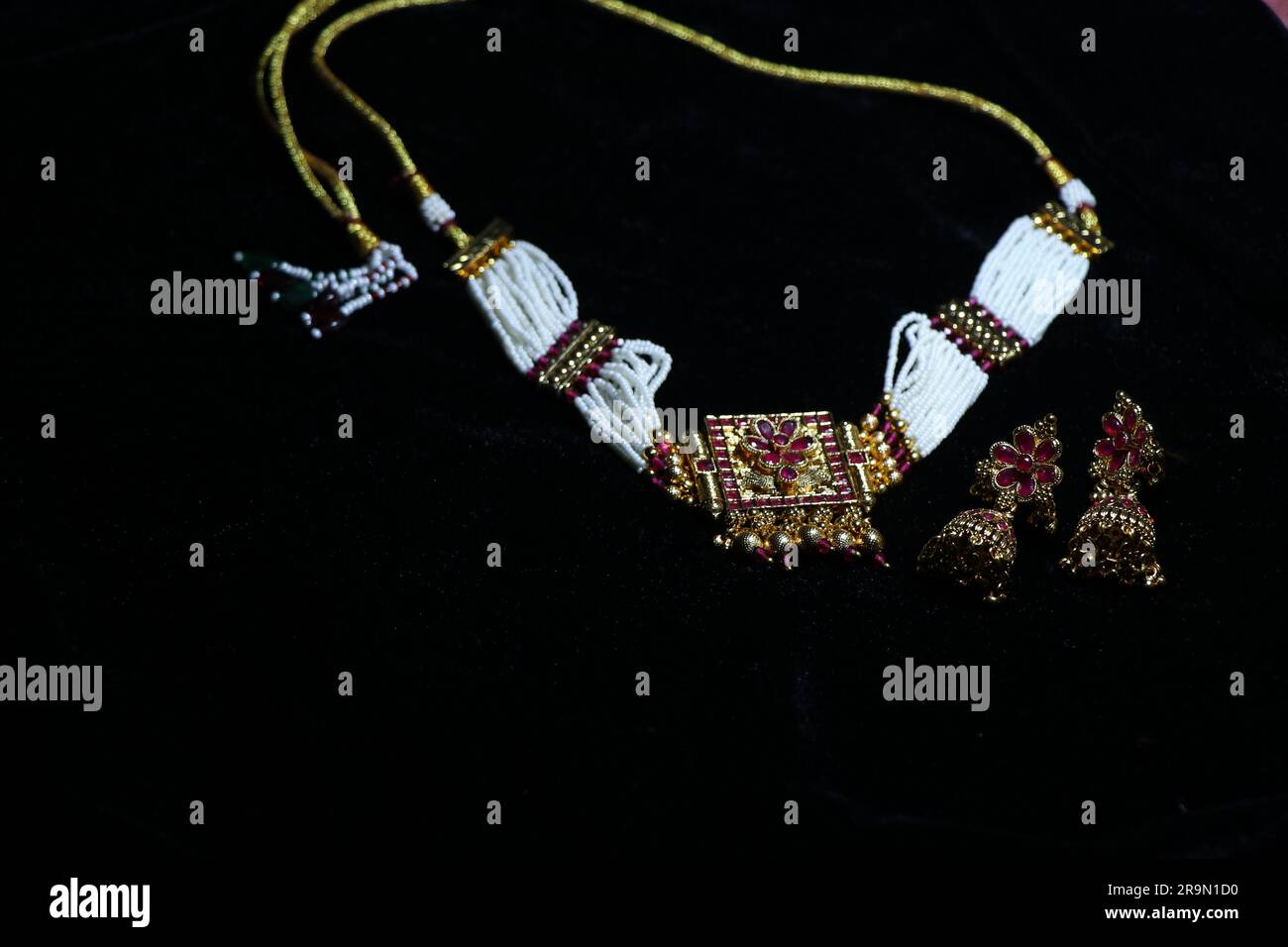 Damenhalskette mit kleinem Ohrring auf fesselndem schwarzem Hintergrund Stockfoto