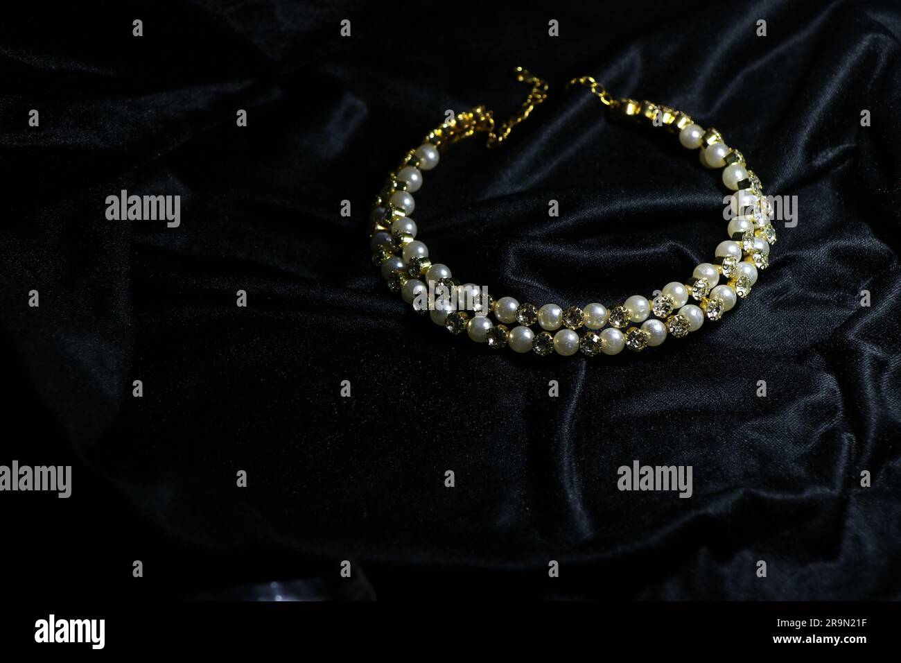 Damenhalskette mit kleinem Ohrring auf fesselndem schwarzem Hintergrund Stockfoto