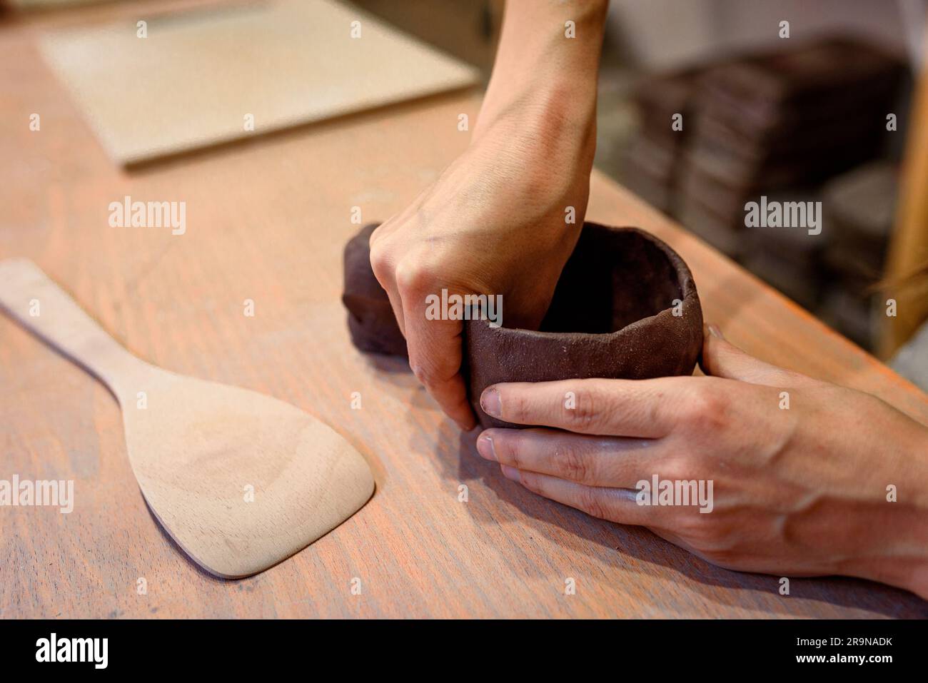 Nahaufnahme von Frauen Töpferhänden funktioniert mit Ton und Keramik, Handwerkerhänden. Kneten und befeuchten Sie den Ton vor der Arbeit in der Keramik- und Keramikwerkstatt Stockfoto