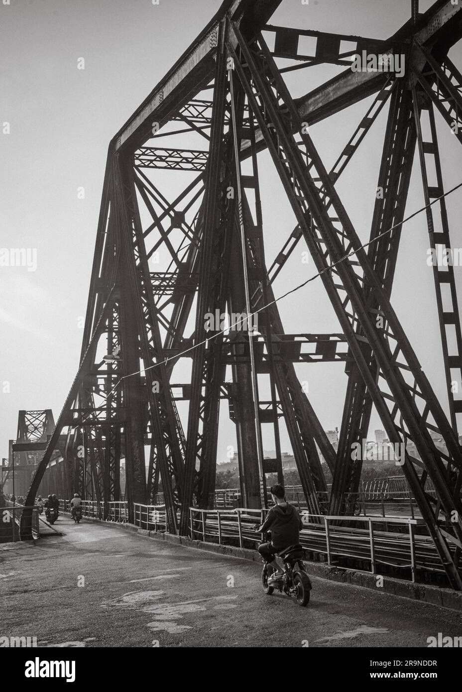 Motorradverkehr überquert die gemeinsame Straße und Eisenbahnbrücke, auch bekannt als Long Bien Bridge in der Dämmerung in Hanoi, Vietnam. Die Brücke stammt aus dem Jahr 1903 und W. Stockfoto