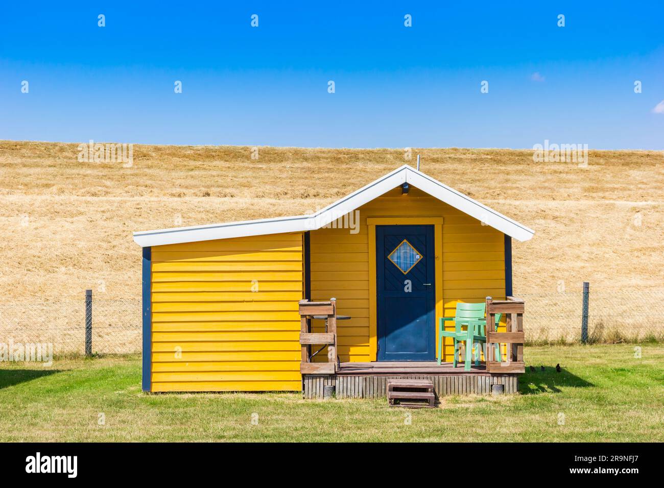 Vorderansicht einer gelben Holzhütte am Deich in Termunterzijl, Niederlande Stockfoto