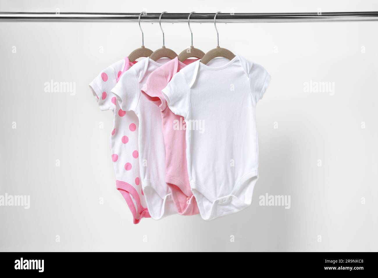 Babykleidung, die an einem Regal in der Nähe der weißen Wand hängt Stockfoto