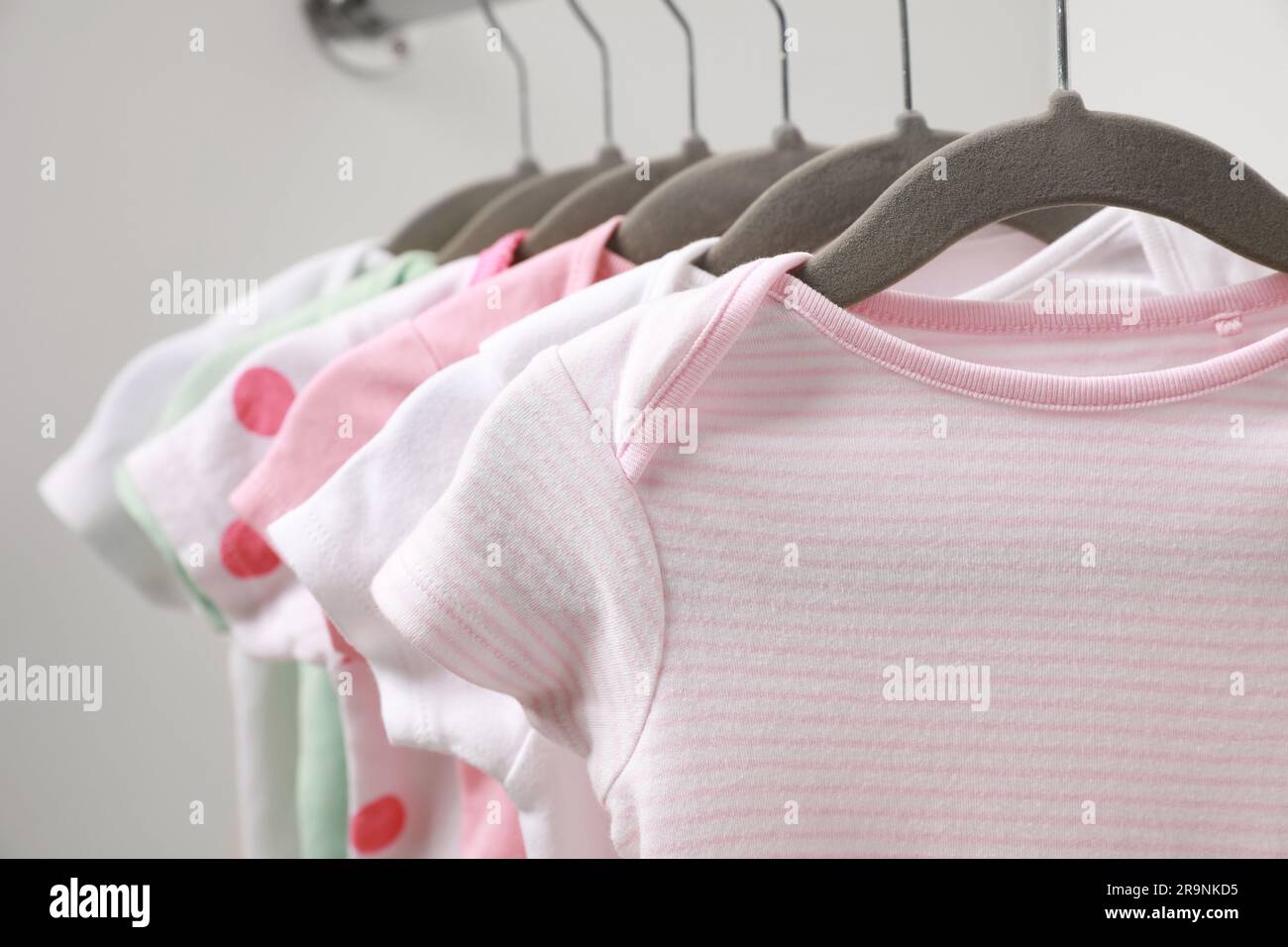 Kleiderbügel mit Babyanzügen auf weißem Hintergrund, Nahaufnahme Stockfoto