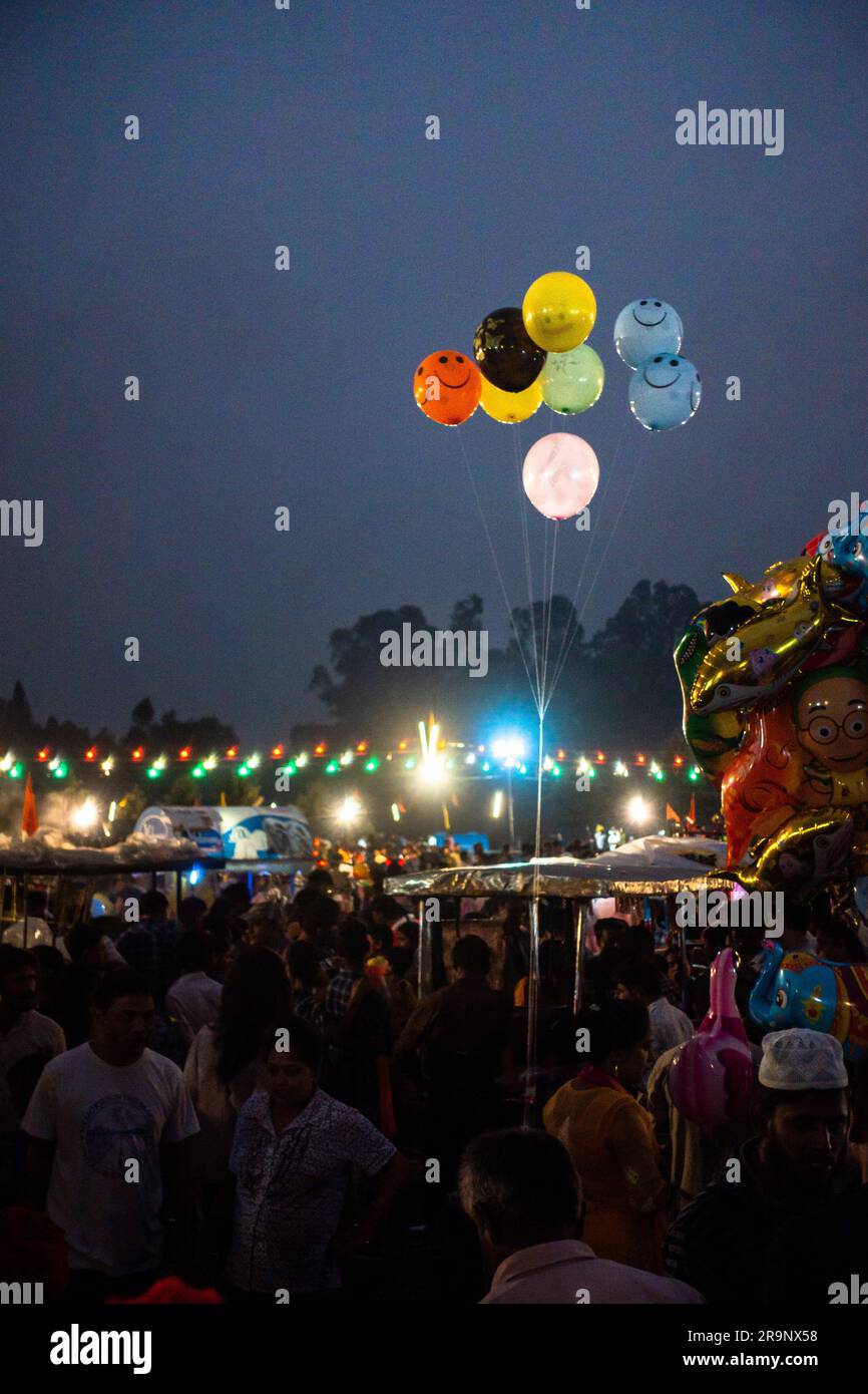 Oktober 19. 2022, Dehradun, Uttarakhand, Indien. Abendliche Aufnahme eines Jahrmarkts mit Blitzlicht und Luftballons in der Luft mit Menschen um sich herum. Stockfoto