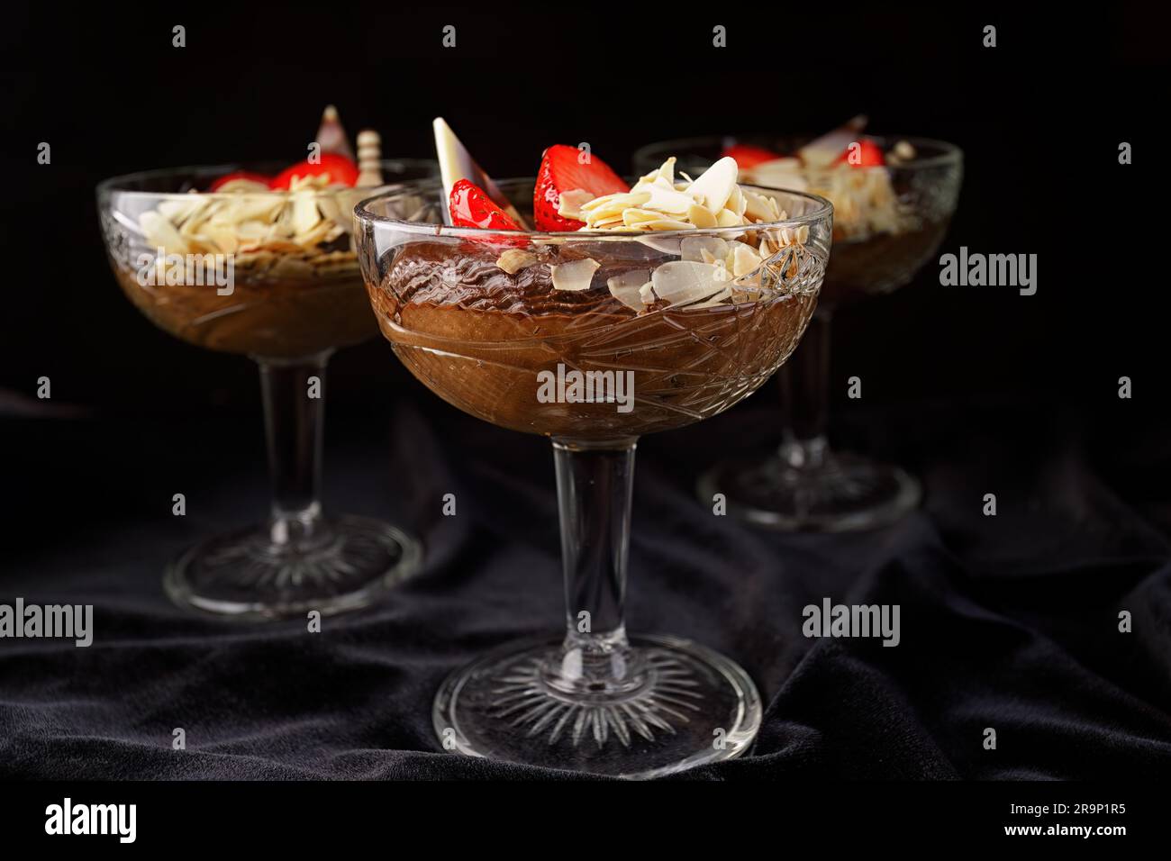 Schokoladendessert mit Erdbeeren auf schwarzem Hintergrund in einer Glasschüssel Stockfoto