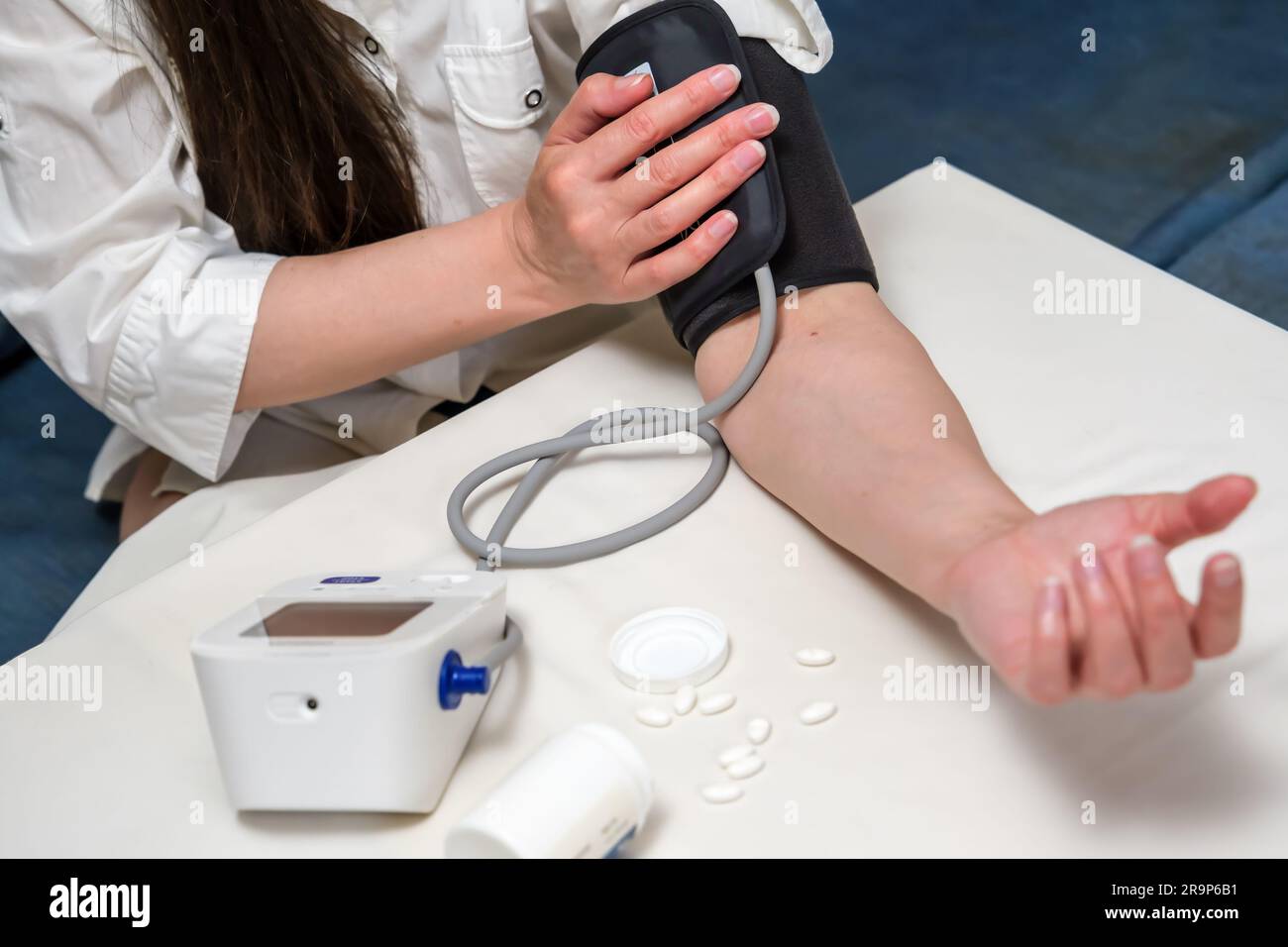 Frau mit modernem Blutdruckmessgerät zu Hause. Blutdruckmessende Frau bei Selbstuntersuchung Stockfoto