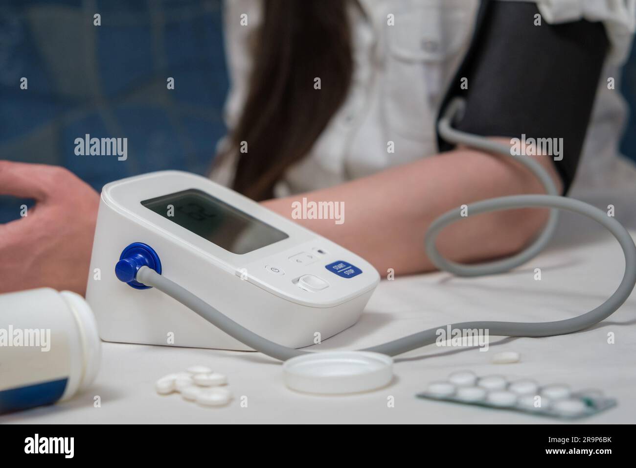 Frau mit modernem Blutdruckmessgerät zu Hause. Blutdruckmessende Frau bei Selbstuntersuchung Stockfoto