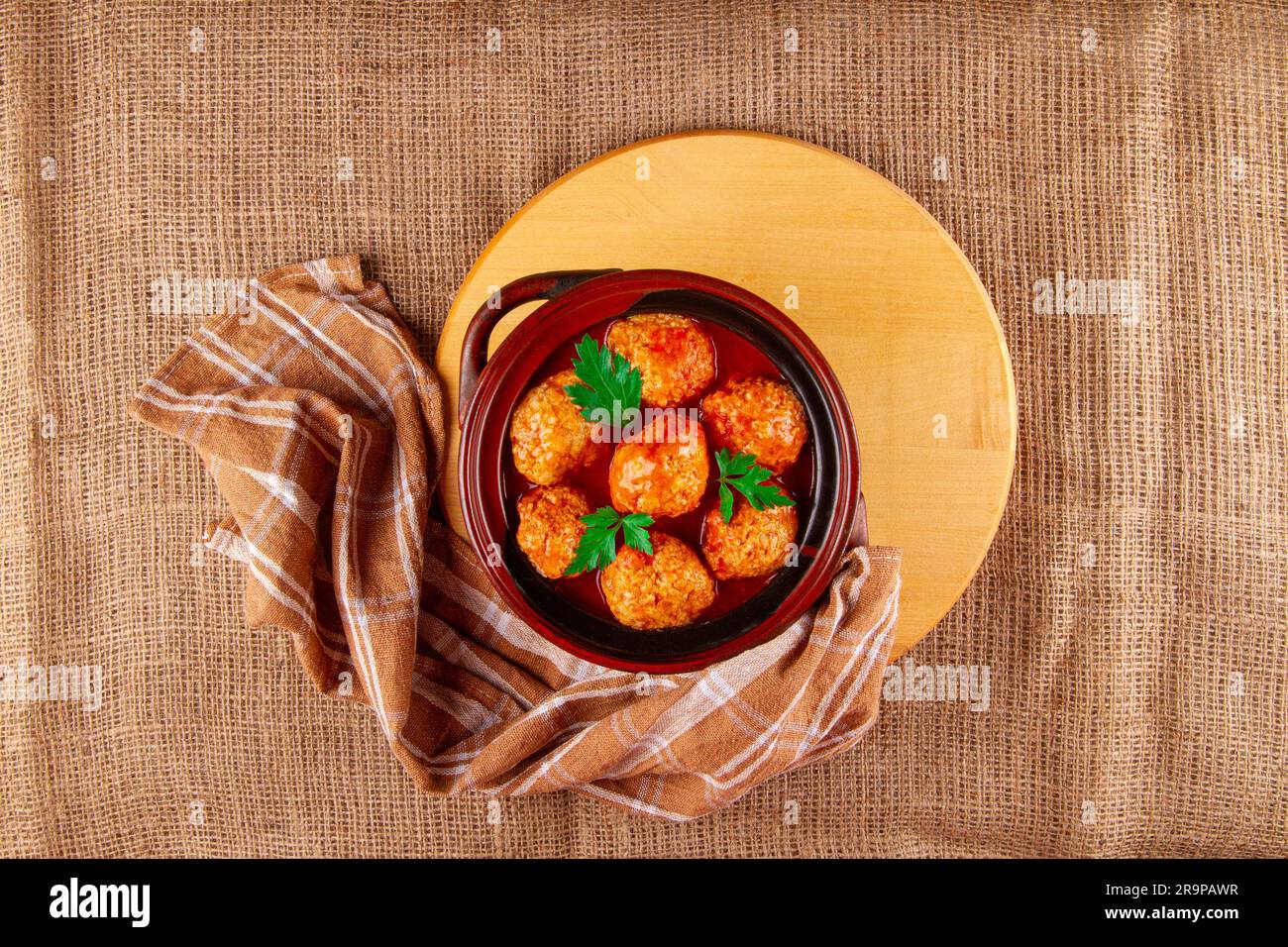 Hähnchenfleischbällchen in Tomatensoße auf Sacktuchhintergrund mit Kopierbereich Stockfoto