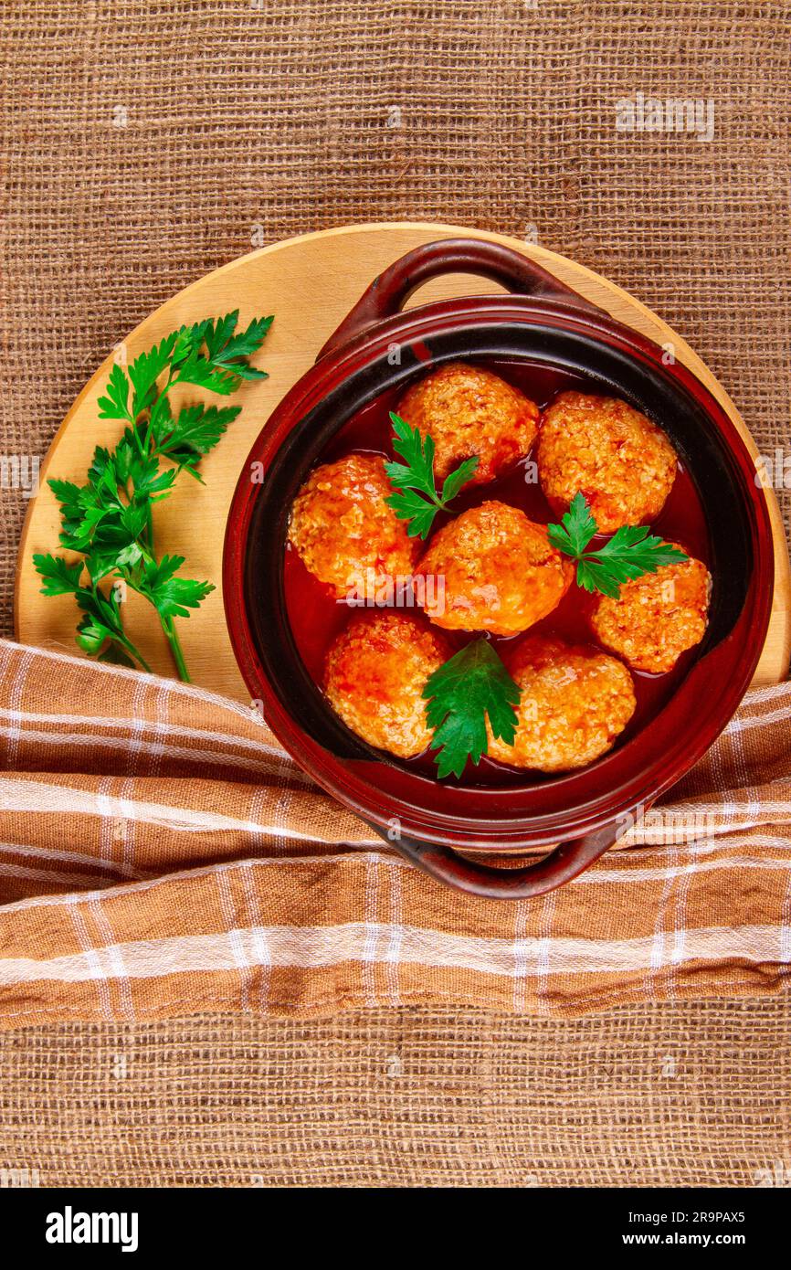 In einem Krümeltopf gekochte Fleischbällchen mit Tomatensoße auf braunem Hintergrund Stockfoto