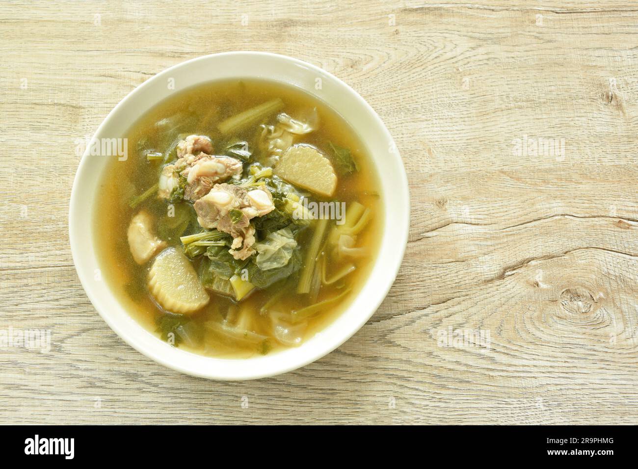 Gekochtes Mischgemüse mit Schweineknochen in schwarzer Sojabohnensuppe auf einem Teller auf dem Tisch Stockfoto