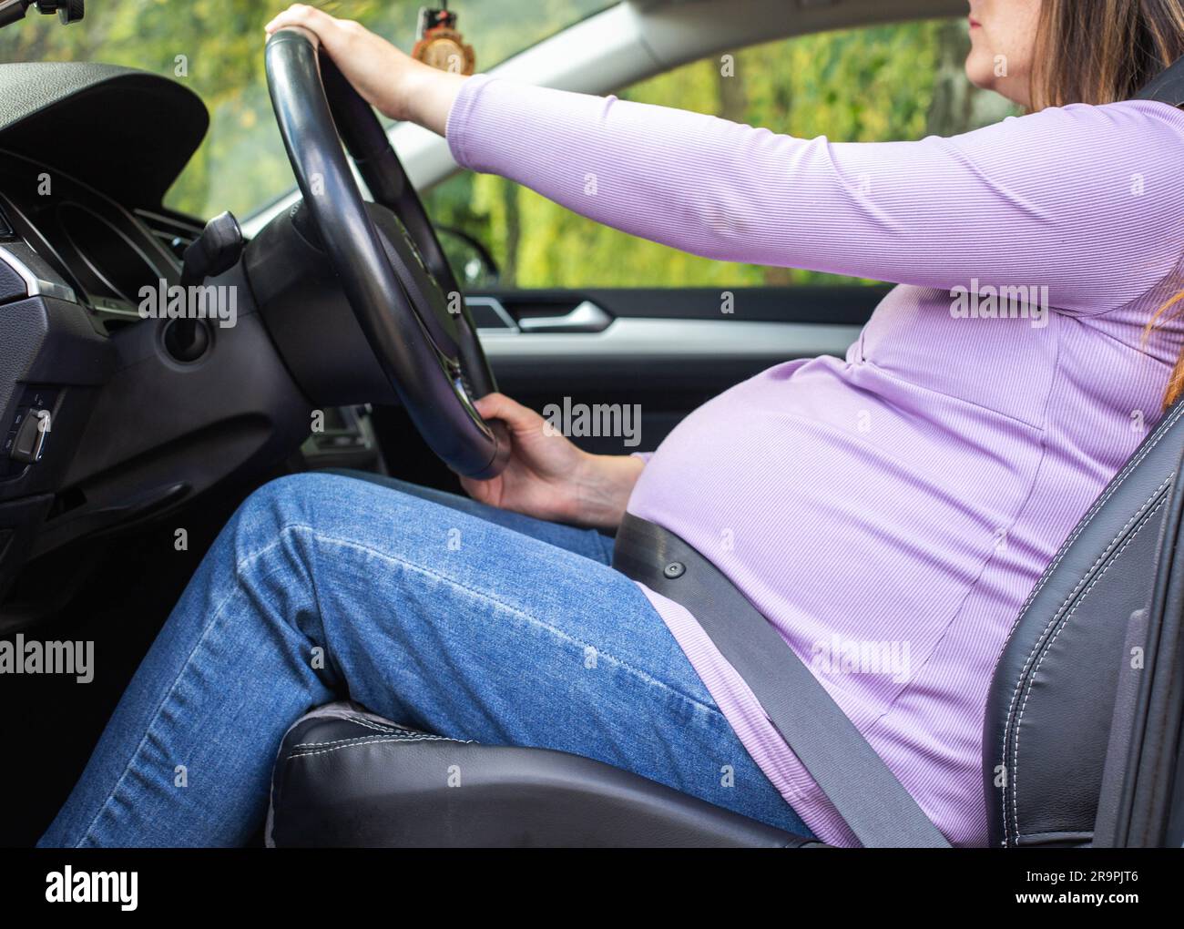 Eine schwangere Frau, die einen Sicherheitsgurt trägt, fährt ein