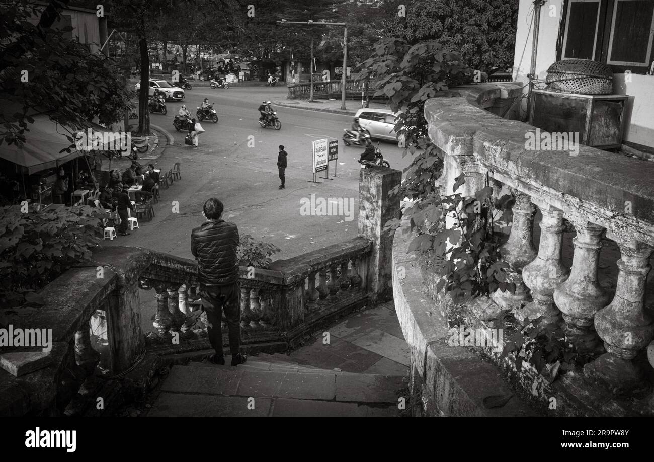 Ein vietnamesischer Mann steht auf den Stufen der französischen Kolonialzeit, die zum Bahnhof Long Bien mit Blick auf die Yen Phu Road in Hanoi, Vietnam, führen. Stockfoto