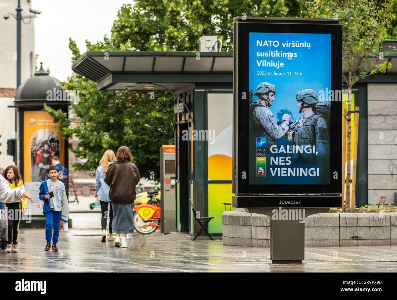 Werbebanner mit Informationen über den bevorstehenden NATO-Gipfel 2023 im Zentrum von Vilnius, der Hauptstadt Litauens, mit Mädchen und Kindern, die zu Fuß unterwegs sind Stockfoto