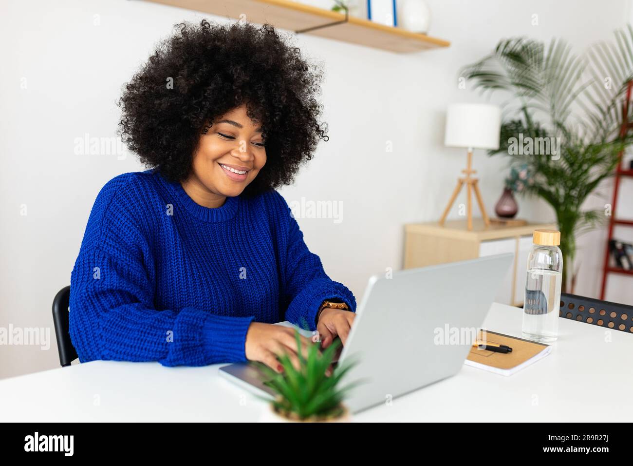Junge, wunderschöne afroamerikanische Frau, die zu Hause einen Laptop benutzt Stockfoto