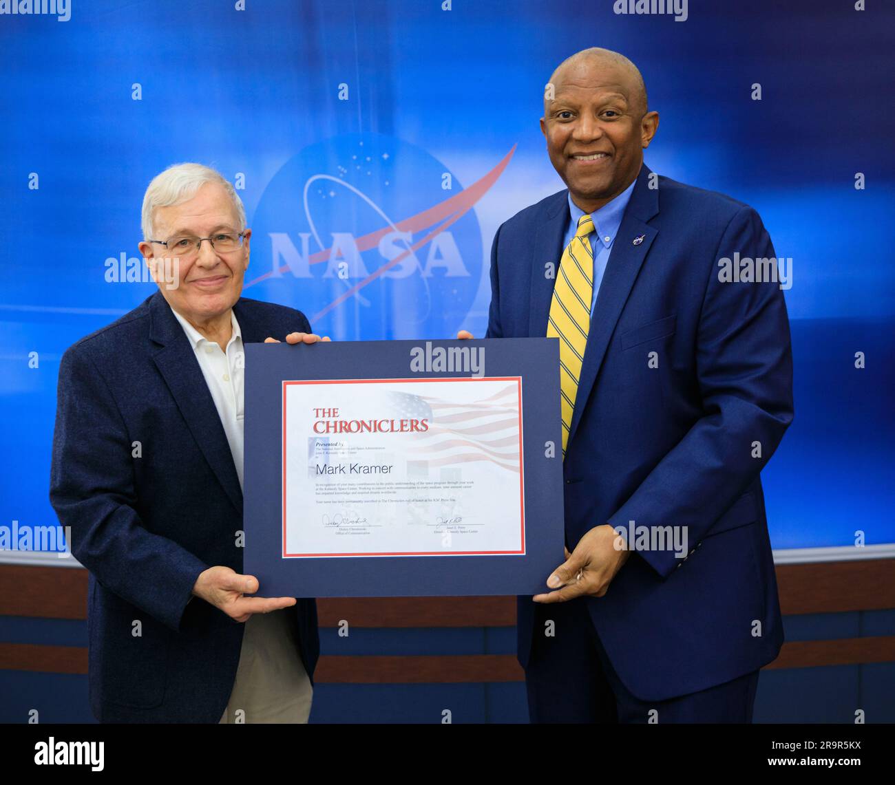 Chronikerzeremonie. Kennedy Space Center Deputy Director Kelvin Manning auf der rechten Seite überreicht Mark Kramer bei einer Zeremonie am 1. Mai 2023 den Chroniclers Award. Er würdigt pensionierte Mitglieder des Nachrichten- und Kommunikationsgeschäfts, die Kennedy 10 Jahre oder länger über die amerikanische Weltraumforschung informiert haben. Kramer wurde zusammen mit Robert E. Granath und Red Huber im Kennedy NASA News Center in Florida mit einer Plakette an der Wand der „Chroniclers“ geehrt. Die Preisträger wurden von anderen Mitgliedern der Nachrichtenmedien nominiert und von einem Gremium von NASA-Beamten und aktuellen Weltraumreportern ausgewählt. T Stockfoto