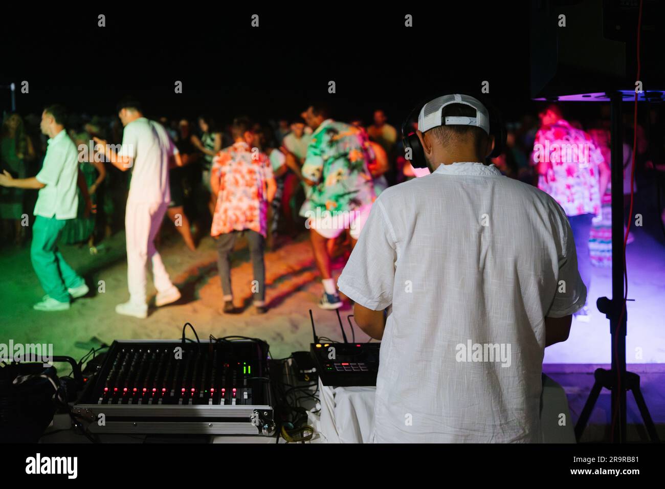 DJ spielt Musik auf einer öffentlichen Party am Strand. Nicht wiedererkennbare Leute tanzen. Stockfoto