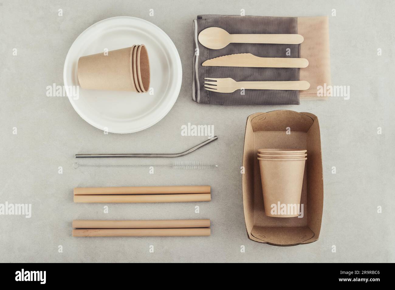 Set aus umweltfreundlichen Geschirr- und Kraftpapier-Lebensmittelverpackungen auf hellem Betonhintergrund. Papierverpackungen für Street Food – Becher, Teller, Pailletten, enthalten Stockfoto