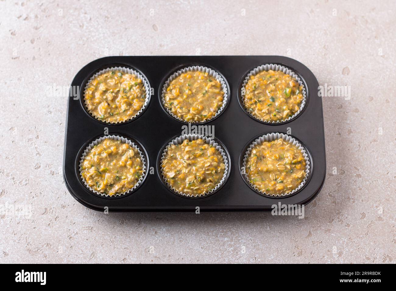 Roher Teig für Kürbismuffins mit Haferbrei und Nüssen in einer Backform mit beigefarbener Struktur. Leckere, gesunde, hausgemachte Kuchen. Stockfoto