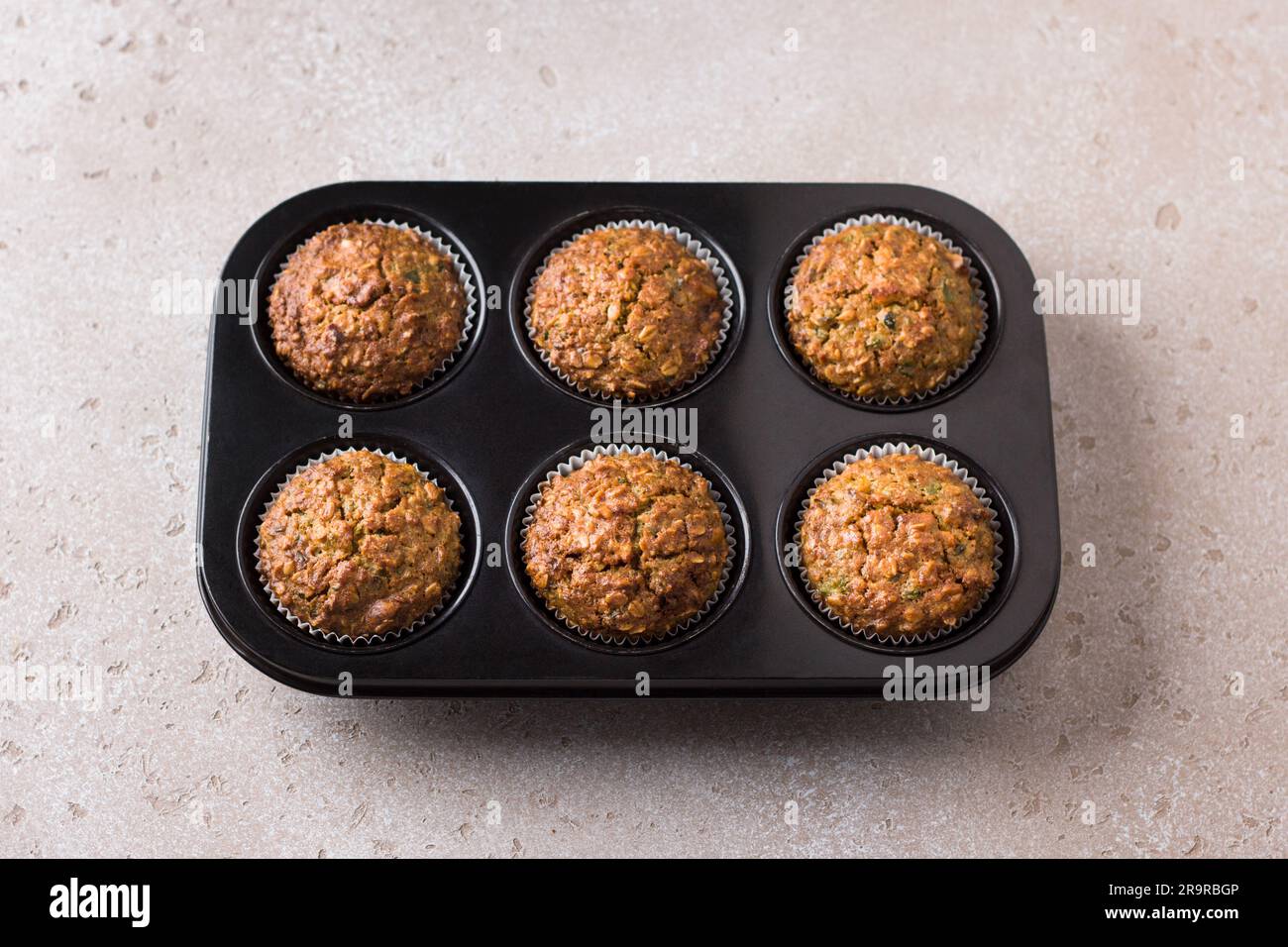 Kürbismuffins mit Haferbrei und Nüssen in einer Backform auf einem beigen strukturierten Hintergrund. Leckere, gesunde, hausgemachte Kuchen. Stockfoto