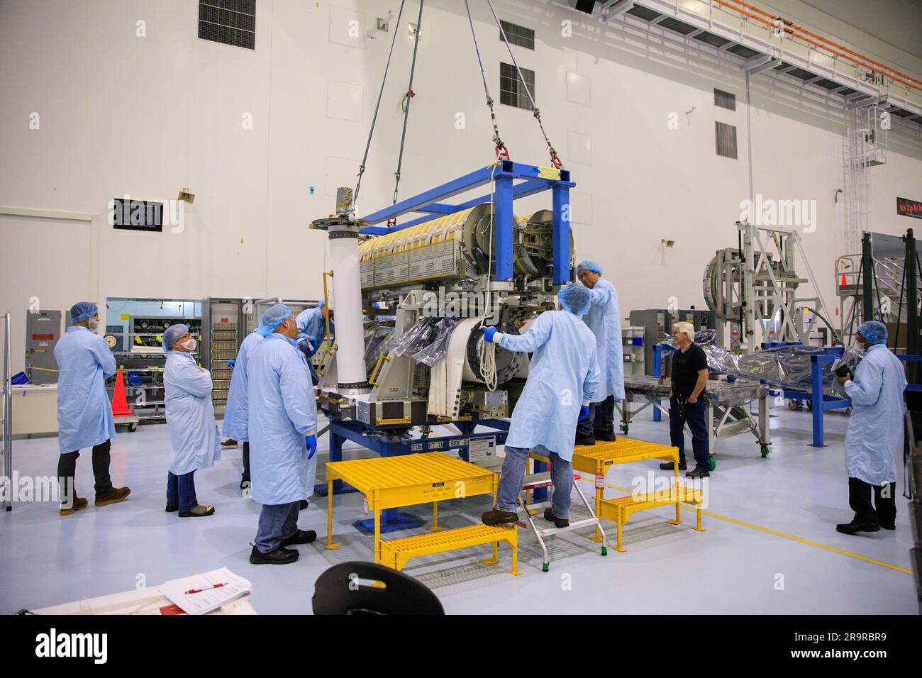 IROSA Hubbetrieb. Im Hochregal der Space Station Processing Facility im Kennedy Space Center der NASA in Florida helfen Techniker, wenn am 23. März 2023 ein Kran zum Absenken einer Reihe von International Space Station Roll Out Solar Arrays (iROSA) auf eine Plattform verwendet wird. Sie werden für die Lieferung an die Raumstation an Bord des Spediteurs Dragon von SpaceX vorbereitet, der 28. kommerzielle Rücklieferungsdienste (CRS-28) des Unternehmens zur Raumstation durchführt. IROSA ist eine neue Art von Solarpaneelen, die sich im Raum öffnen lassen und kompakter als aktuelle starre Platten sind. Stockfoto