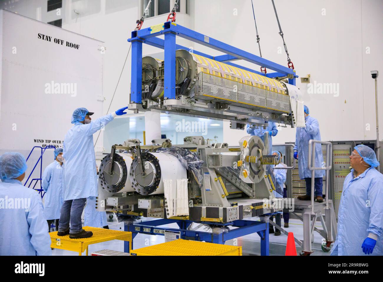 IROSA Hubbetrieb. Im Hochregal der Space Station Processing Facility im Kennedy Space Center der NASA in Florida helfen Techniker, wenn am 23. März 2023 ein Kran zum Anheben und Stapeln der dritten Gruppe von zwei International Space Station Roll Out Solar Arrays (iROSA) auf einer Plattform verwendet wird. Sie werden für die Lieferung an die Raumstation an Bord des Spediteurs Dragon von SpaceX vorbereitet, der 28. kommerzielle Rücklieferungsdienste (CRS-28) des Unternehmens zur Raumstation durchführt. IROSA ist eine neue Art von Solarpaneelen, die sich im Raum öffnen lassen und kompakter als aktuelle starre Platten sind. Stockfoto