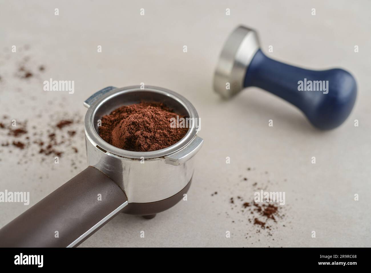 Portafilter mit Kaffee und Temperament auf hellem Betonhintergrund Stockfoto