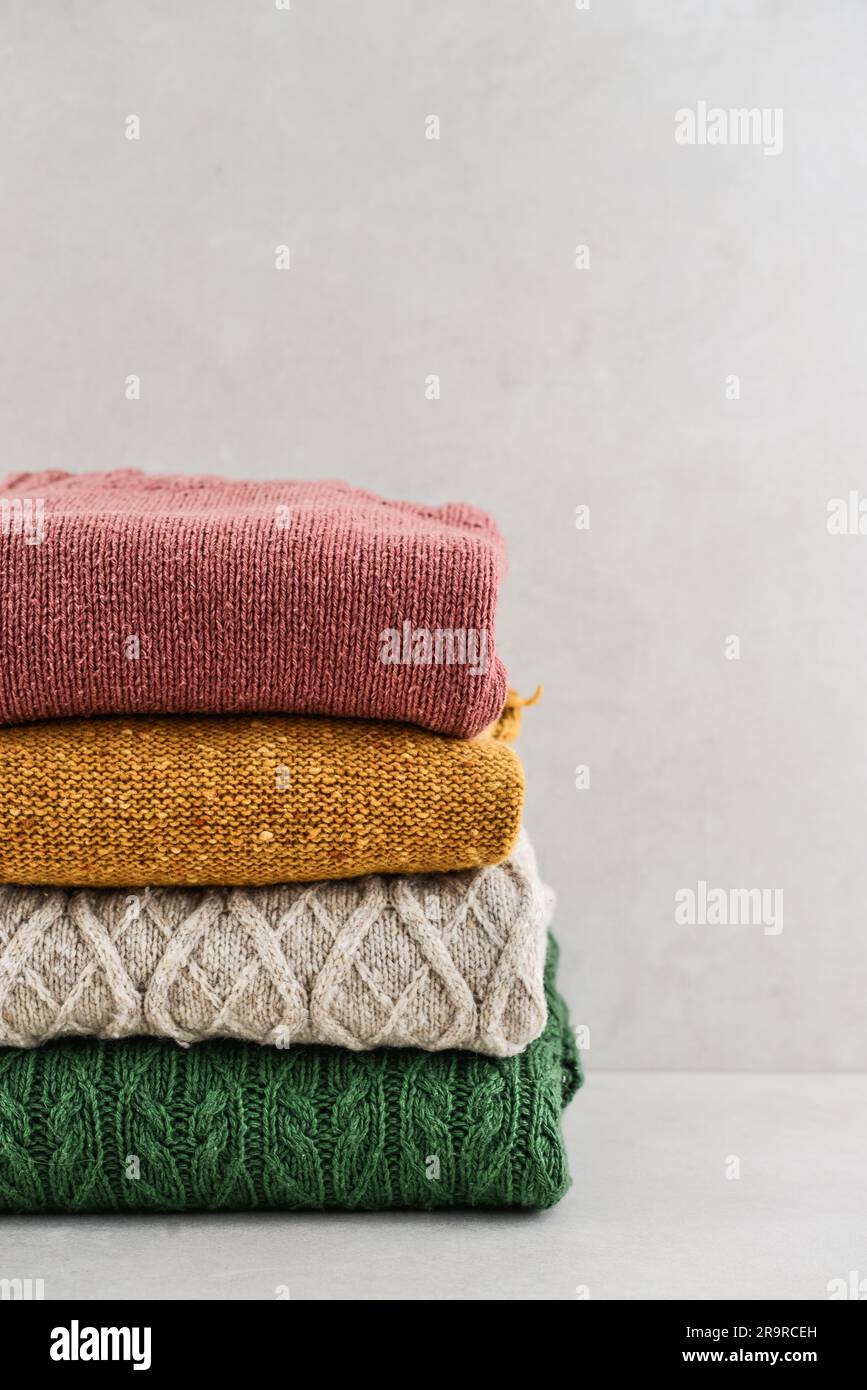 Ein Haufen handgestrickter Winterkleidung auf hellem Hintergrund: Pullover, Strickwaren, Platz für Text Stockfoto