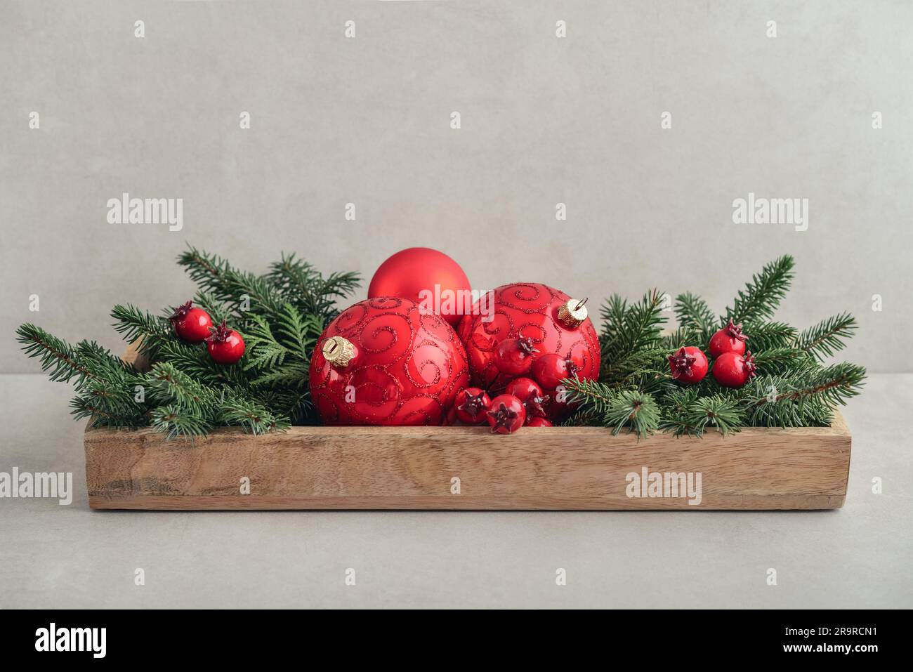 Weihnachtsdekorationen aus Tannenzweigen und roten weihnachtskugeln in Holzkiste auf hellem Hintergrund Stockfoto
