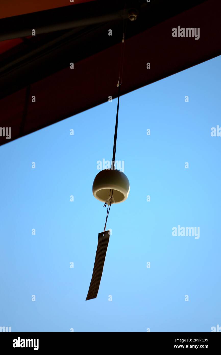 Der Dachvorsprung eines Ladens, in dem ein Windspiel namens „Furin“, eine japanische Sommertradition, aufgehängt wird. Stockfoto