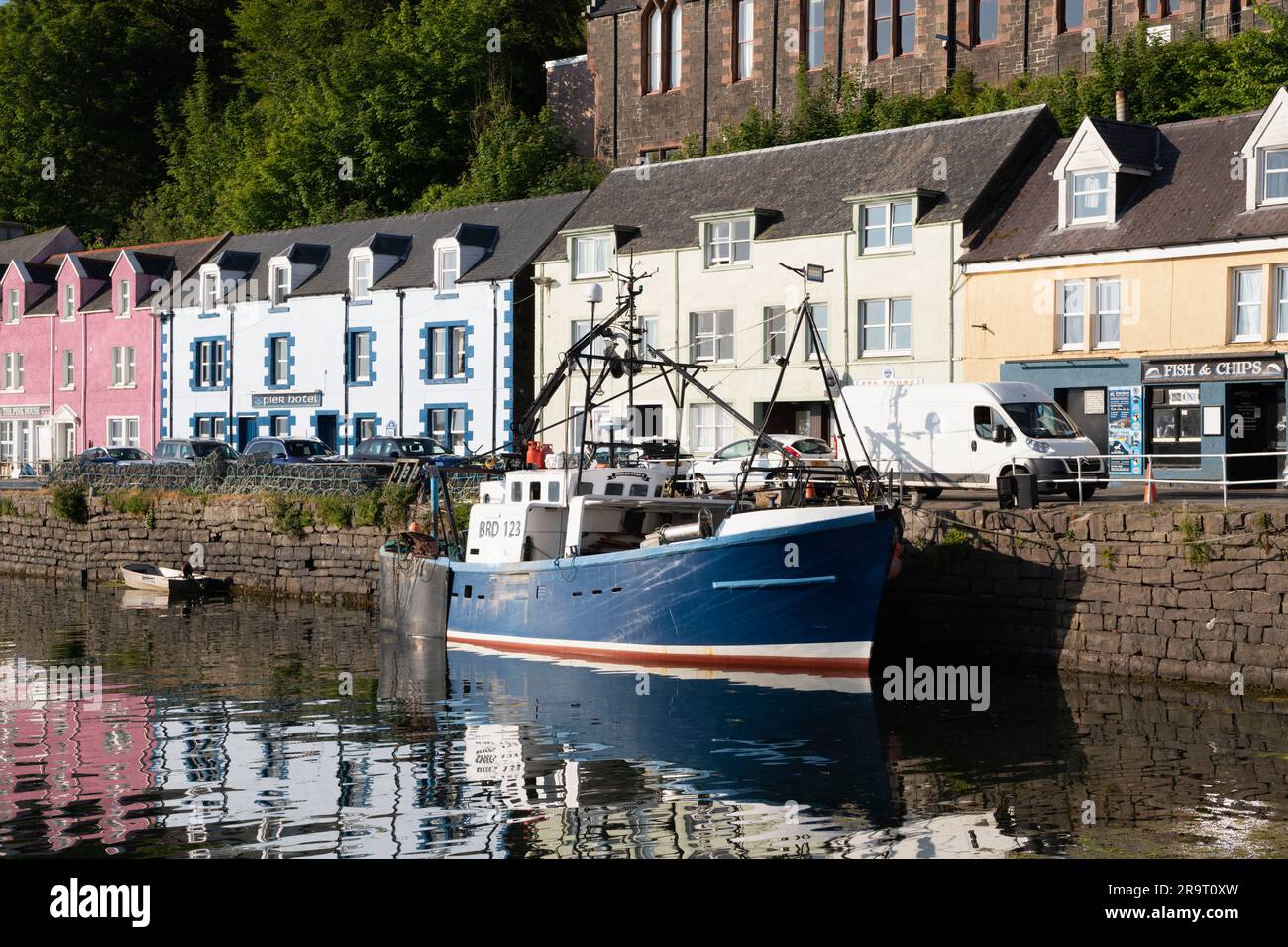 Ein Fischerschiff (Dunan Star II), das am Kai in Portree Harbour, Isle of Skye, vor den bunten Gebäuden in der Quay Street festgemacht ist. Stockfoto