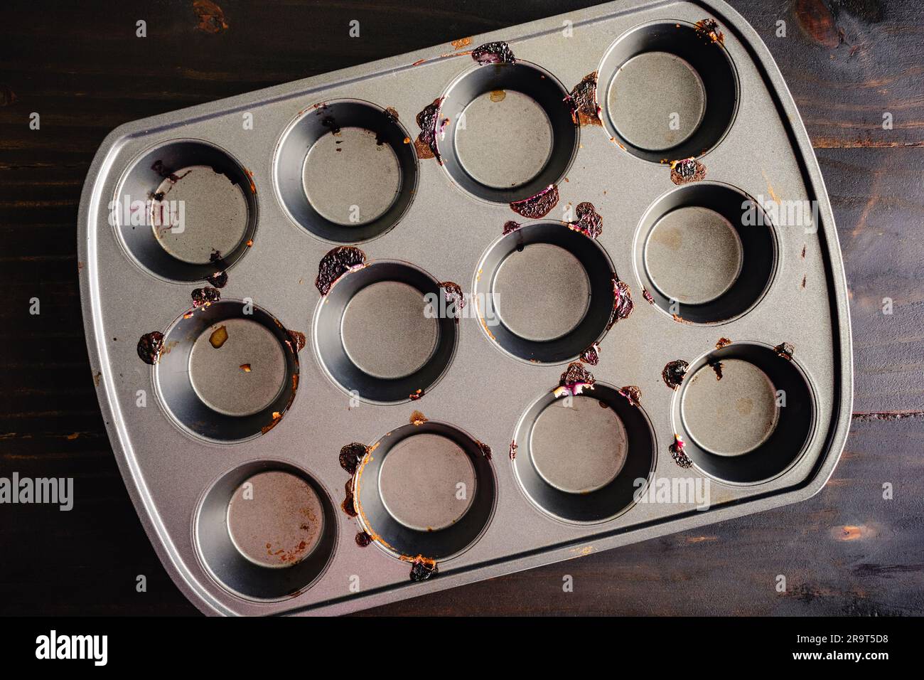 Leere dreckige Muffin-Pfanne von oben gesehen: Muffin-Dose, die für Blaubeermuffins verwendet und nicht gereinigt wurde Stockfoto