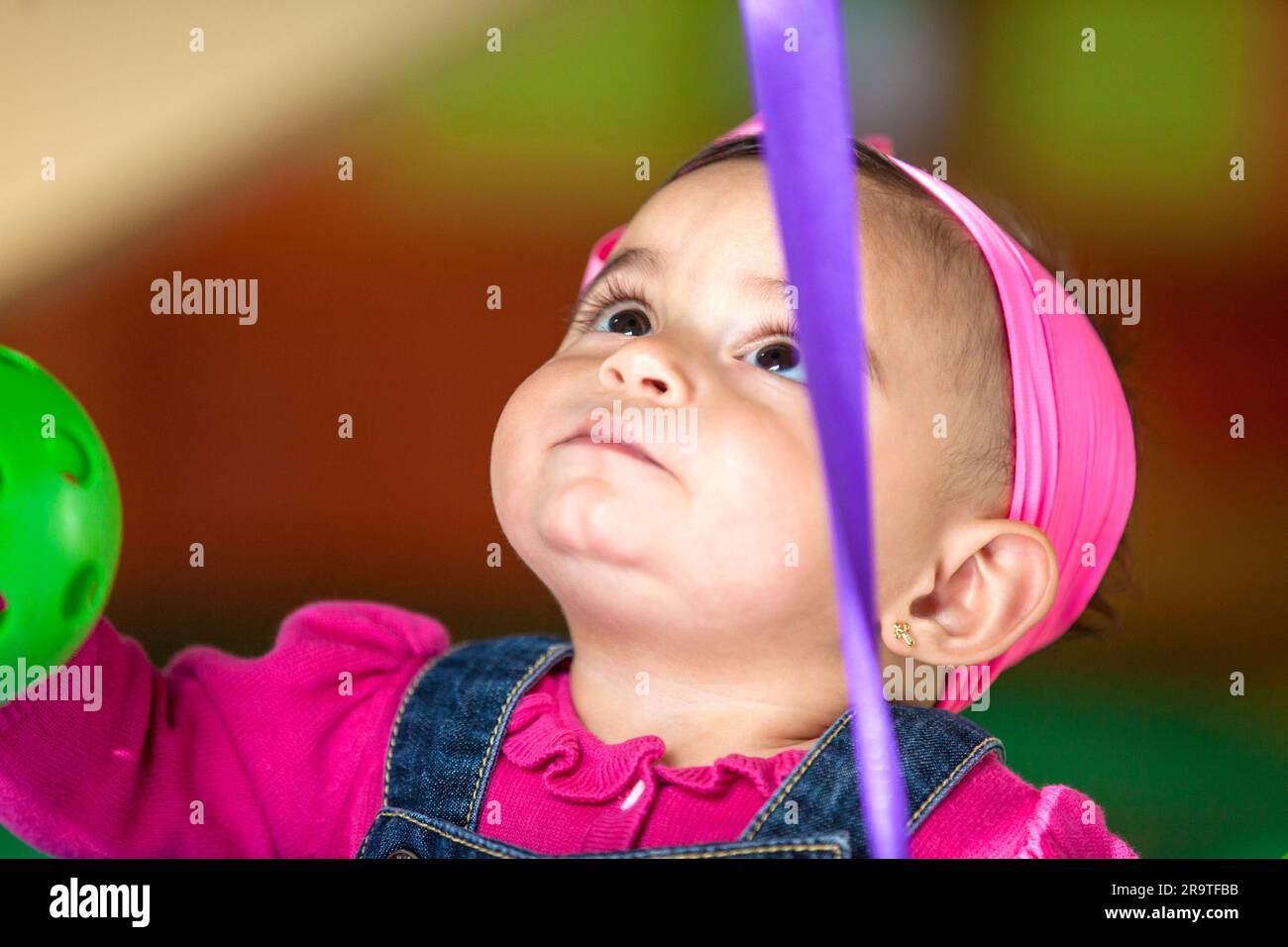 Ein wunderschönes 10 Monate altes Mädchen, das mit bunten Bällen spielt. Frühstimulierungs-Konzept für Kleinkinder. Stockfoto