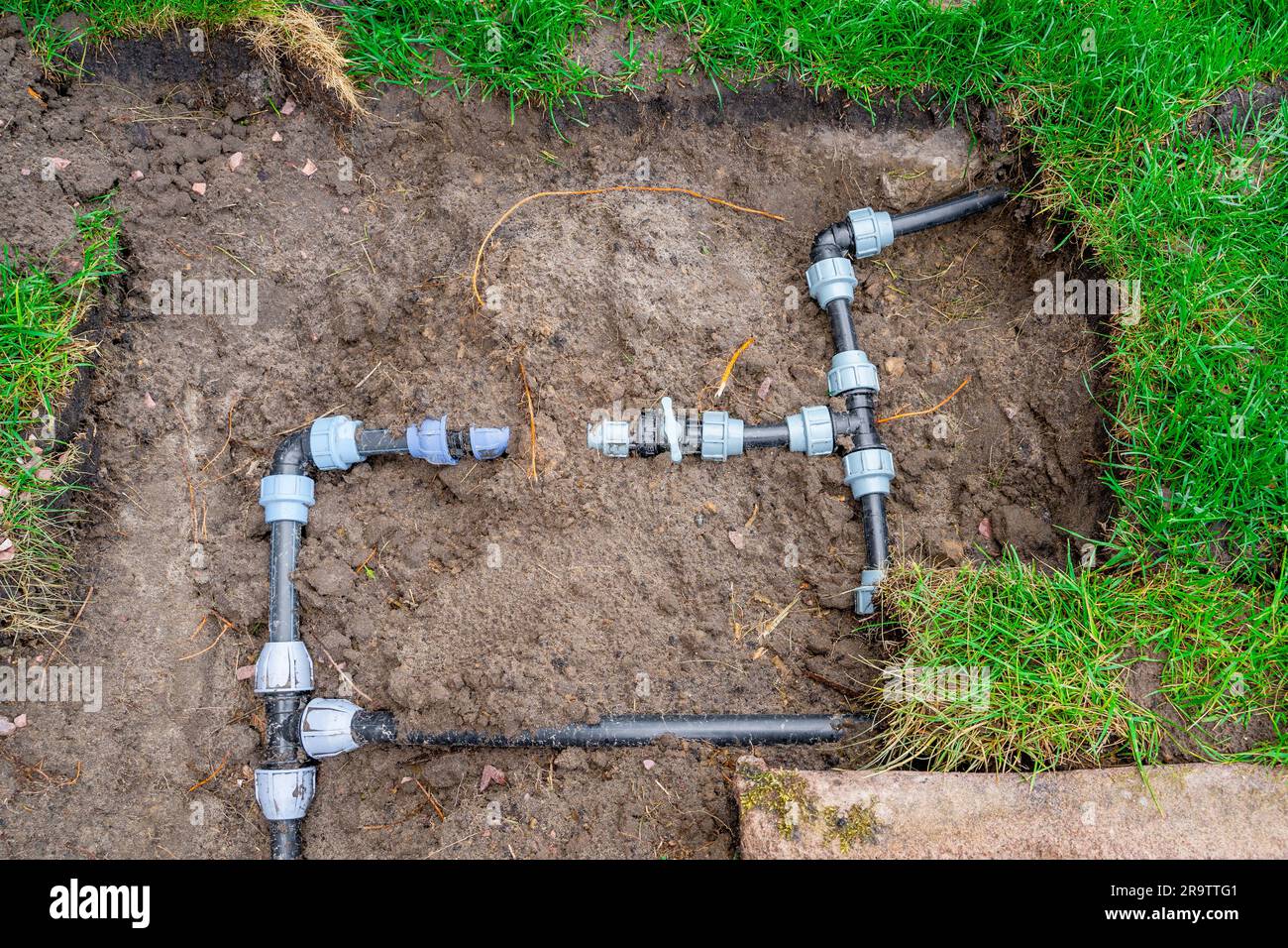 Kunststoffrohre und Stromkreisverkabelung für die Rasenbewässerung. Anschlussarmaturen und Ventile zum Absperren von Wasser im Garten Stockfoto