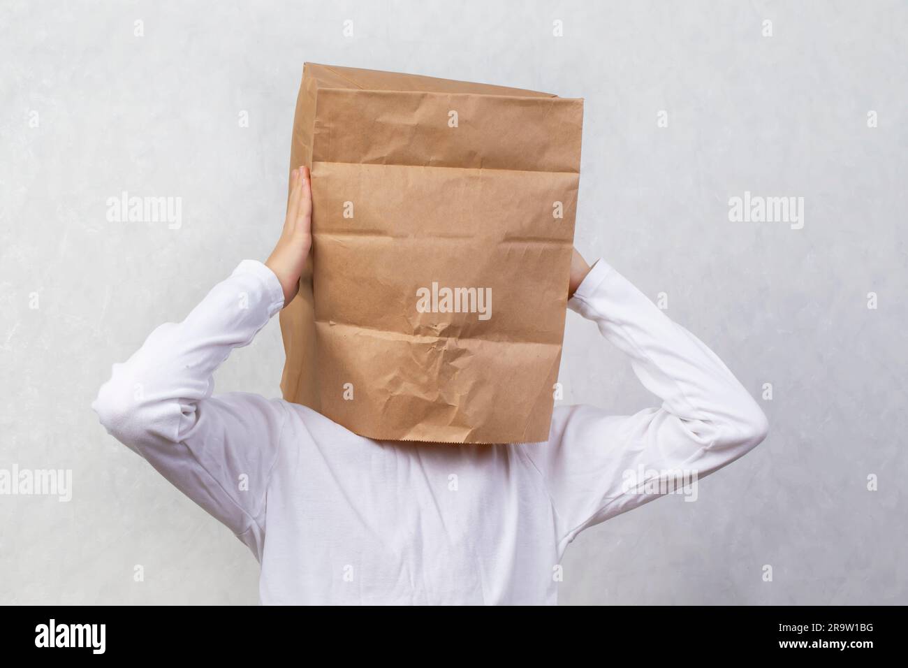 Ein anonymer Mann mit einer Kiste auf dem Kopf, die seine Identität einschränkt. Verborgene Emotionen. Stockfoto