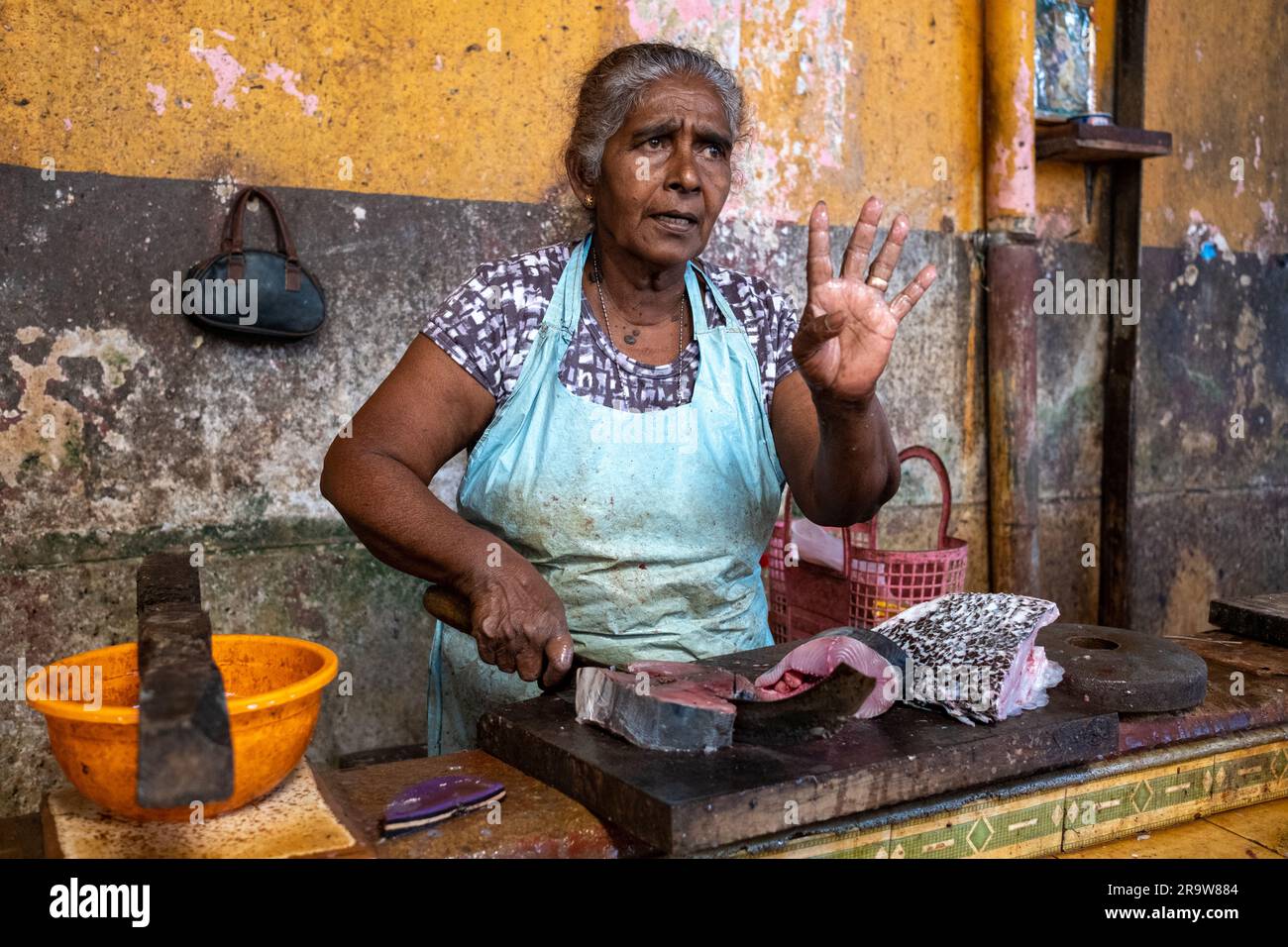 Eine Marktfrau schneidet Fisch auf einem Fischmarkt in Colombo, Sri Lanka Stockfoto