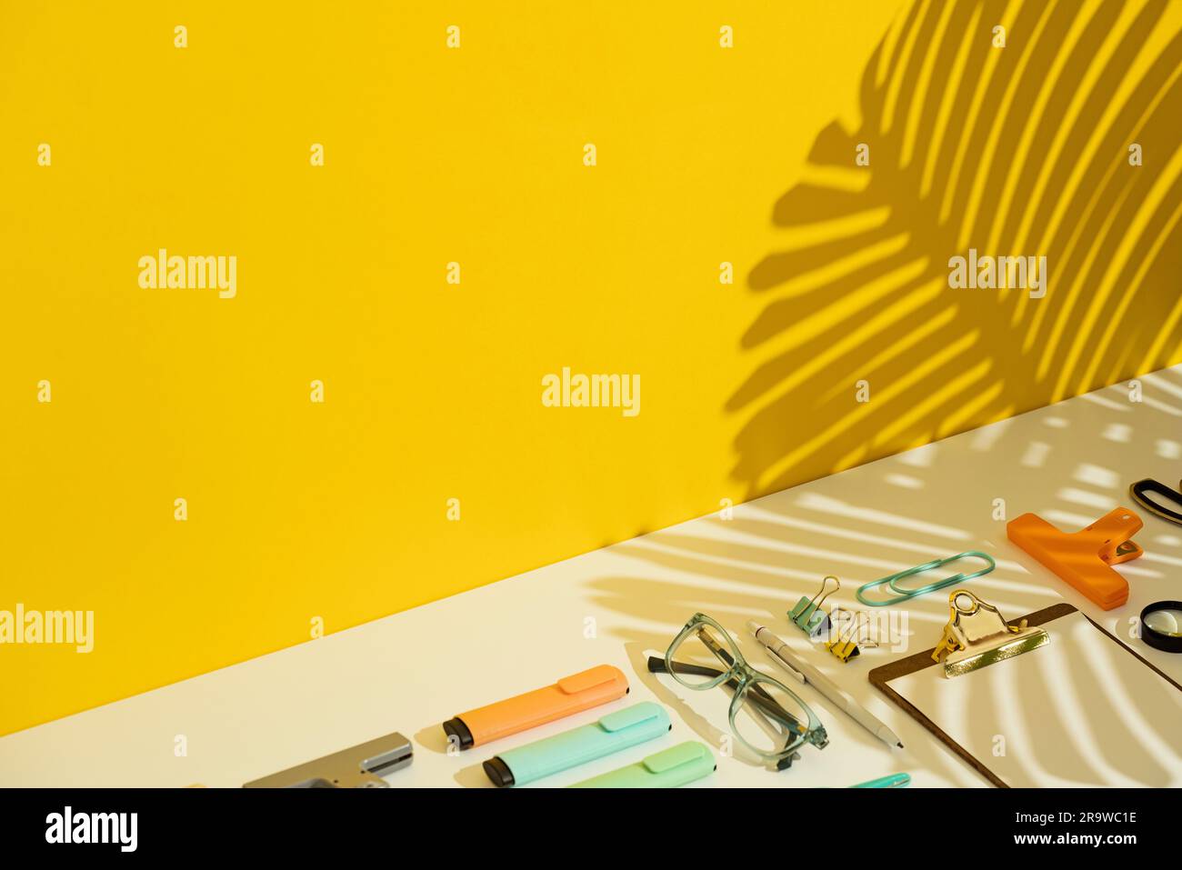 Stationär flach liegend auf gelbem und weißem Hintergrund mit Palmenblättchen-Schatten. Stockfoto