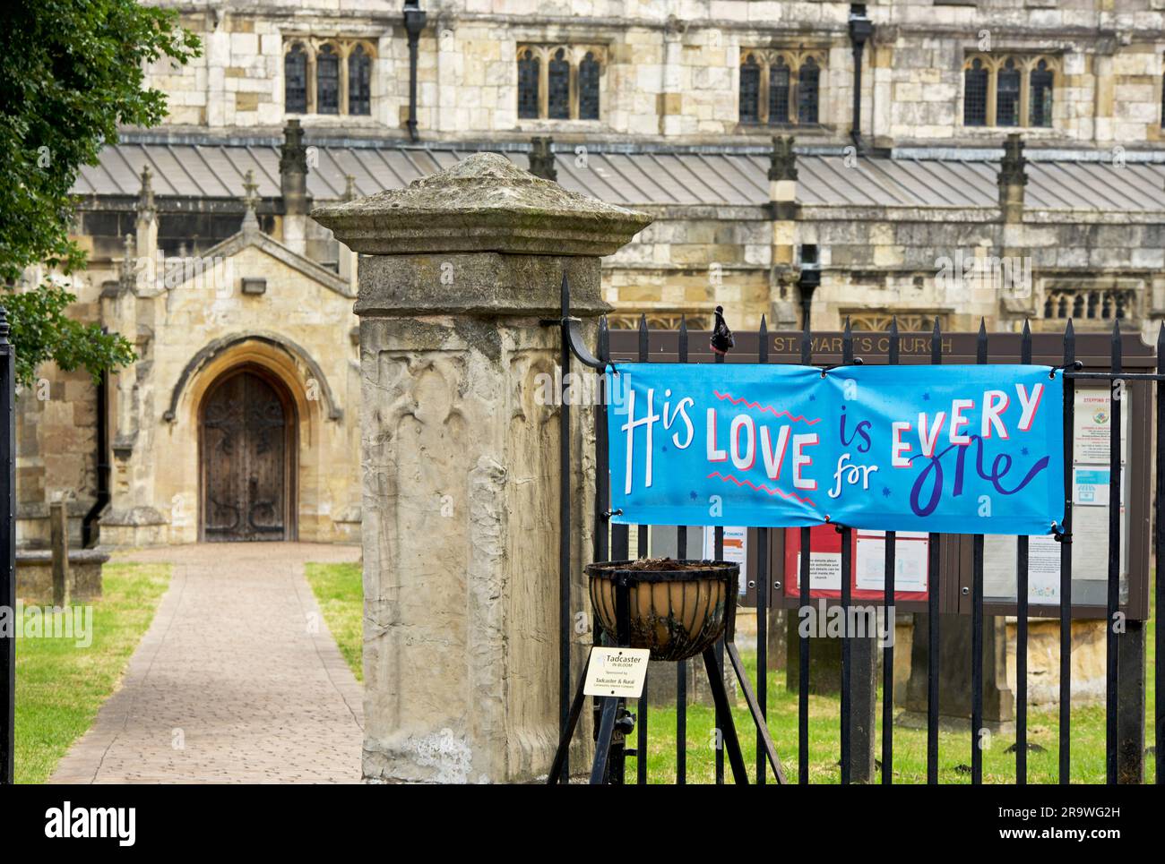 Banner – seine Liebe gilt allen – vor der St. Mary's Church, Tadcaster, North Yorkshire, England, Großbritannien Stockfoto